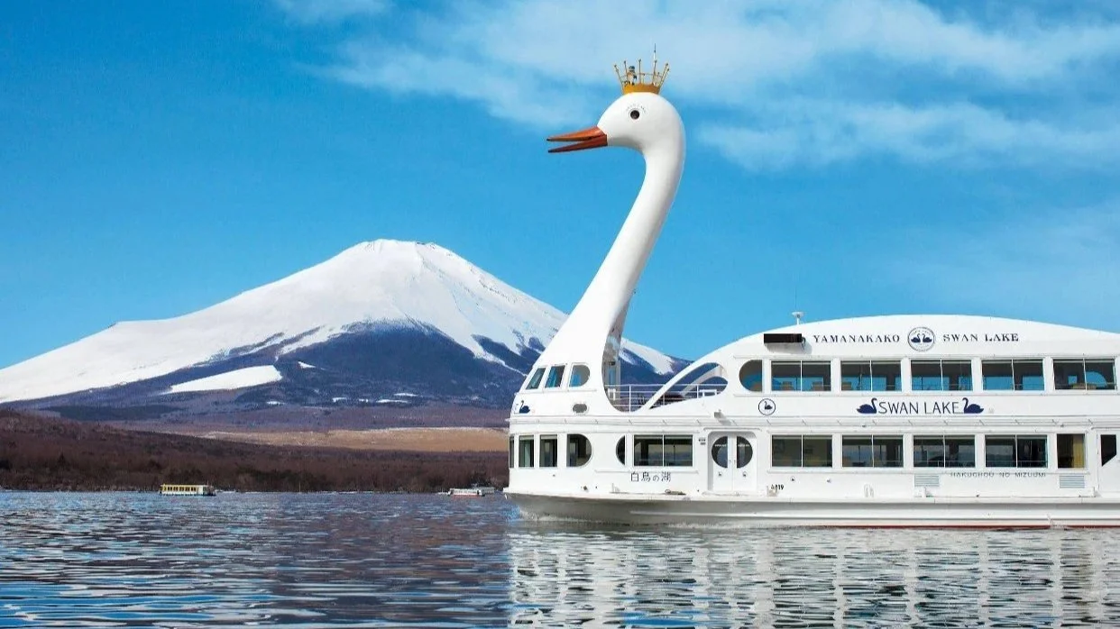 Snow-capped Mt Fuji above a lake with a swan-shaped sightseeing boat, Japan