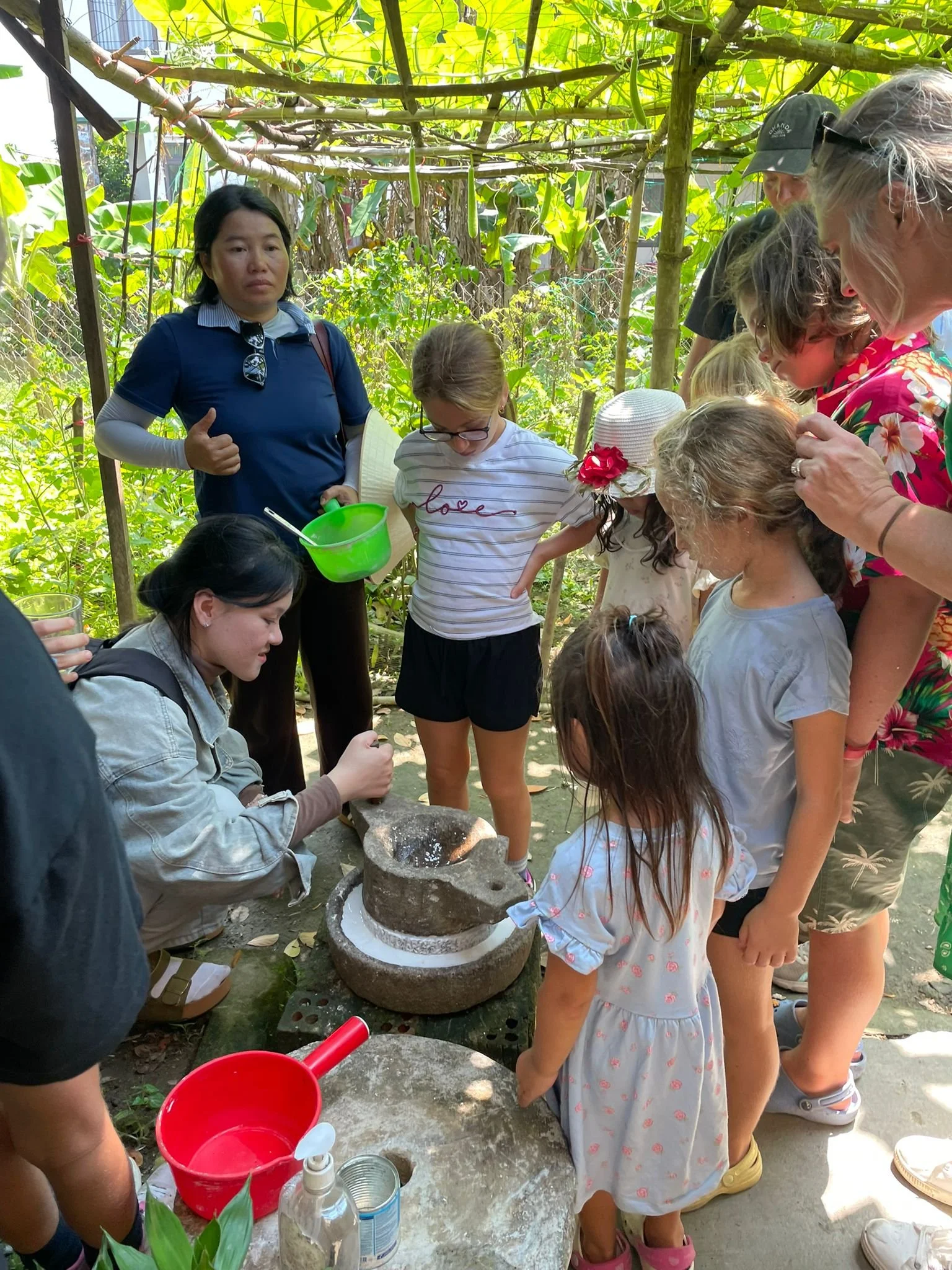 Children and parents on a family group travel tour learning a traditional grinding activity outdoors