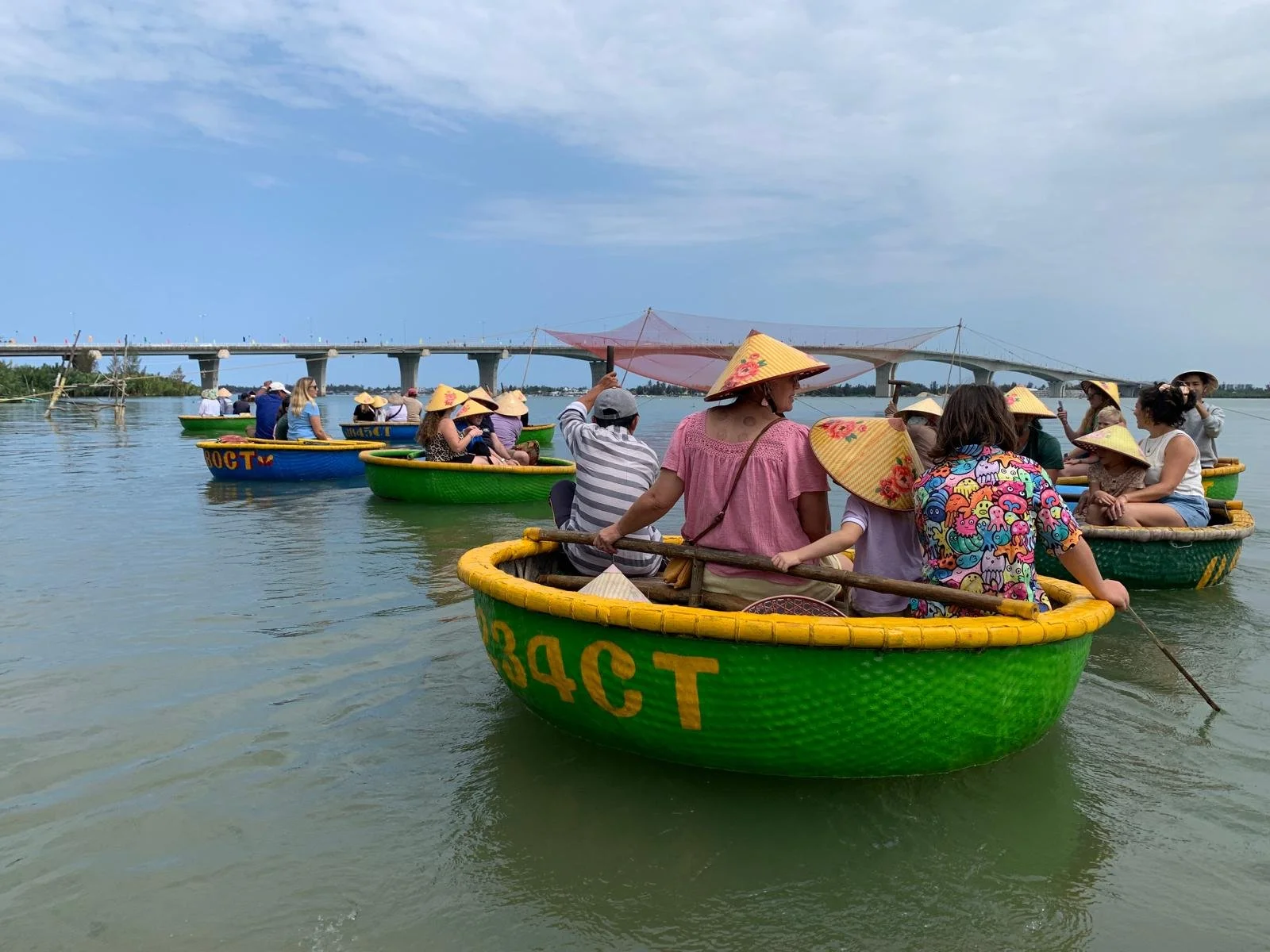 Families on a group travel tour riding traditional round basket boats on a river in Vietnam