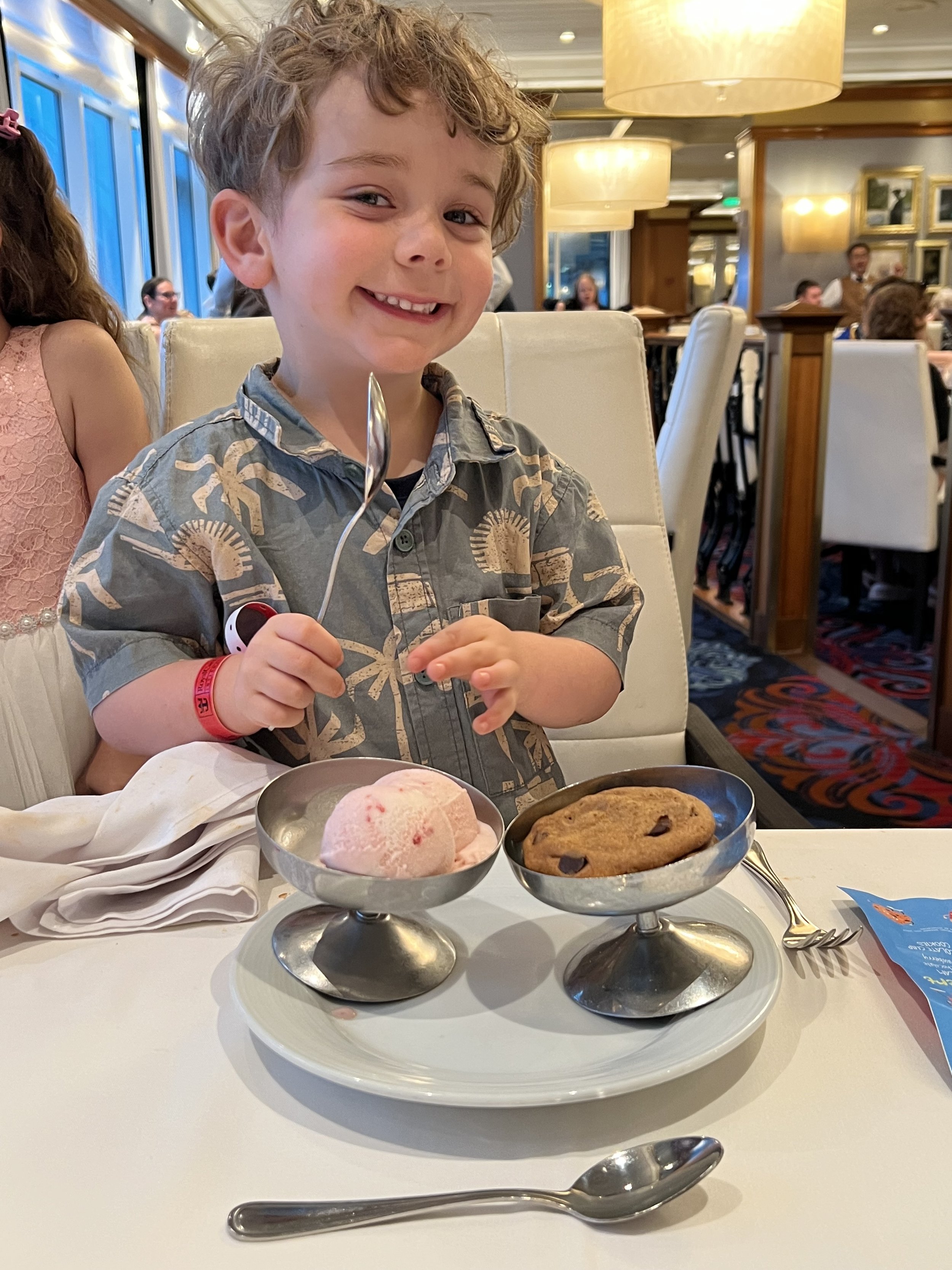 Young boy grinning over ice cream and a cookie in the cruise ship dining room