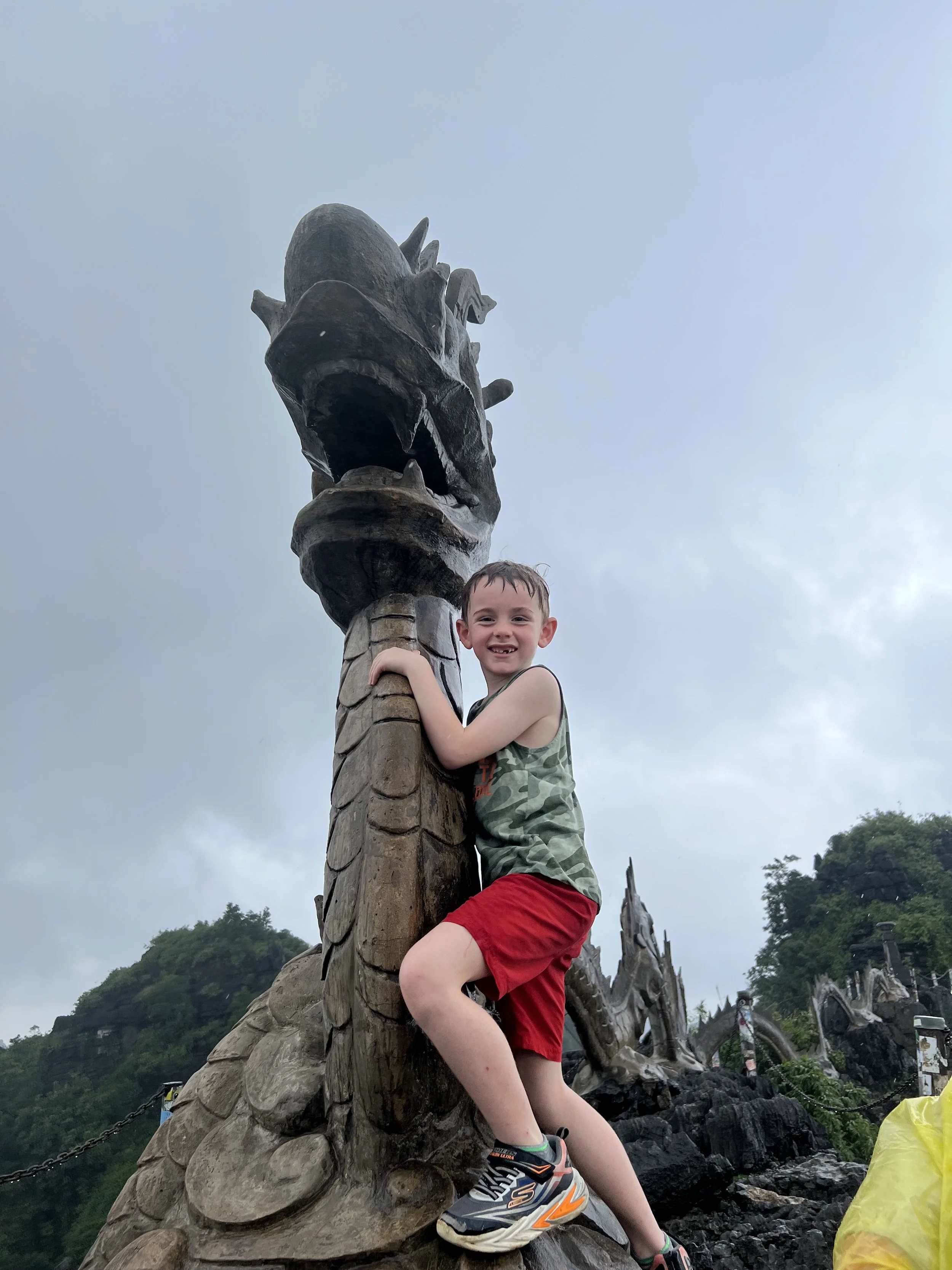 Boy standing beneath the stone dragon statue at the top of Hang Mua, Ninh Binh