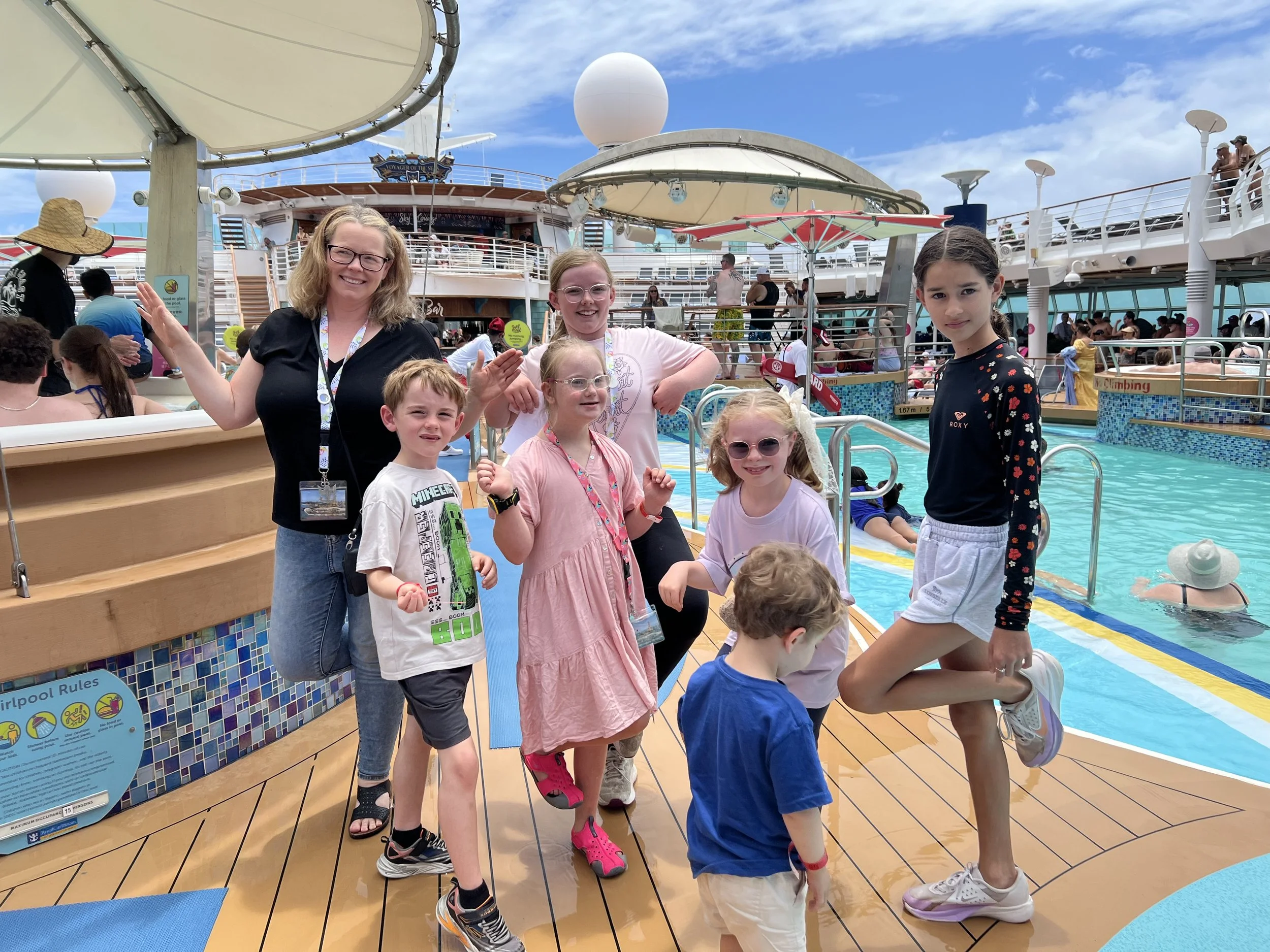 Worldschooling families and kids posing together on the sunny pool deck of the cruise ship