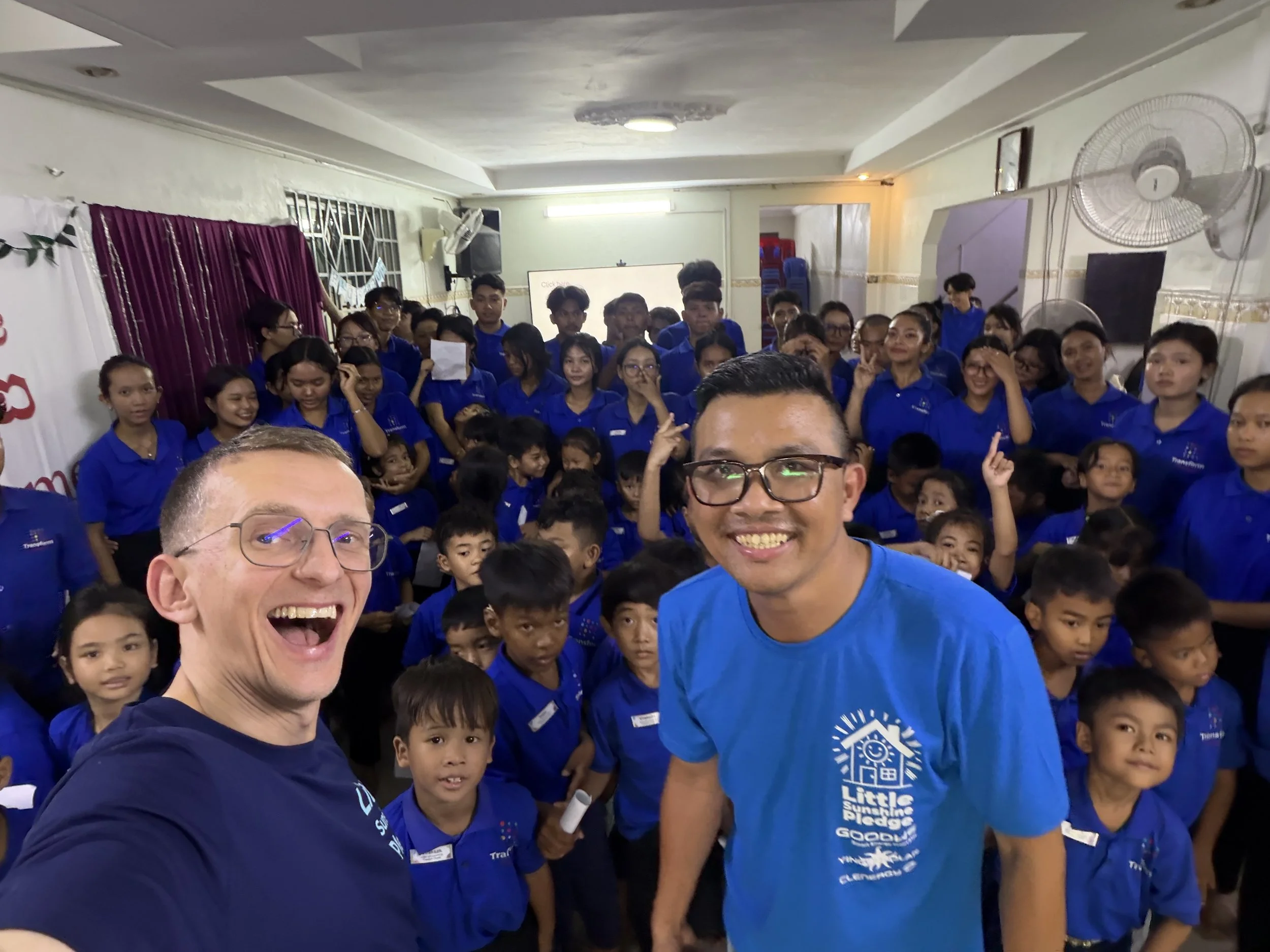 LSP team members standing in one of the rooms of Transform Cambodia with lots of kids in the background