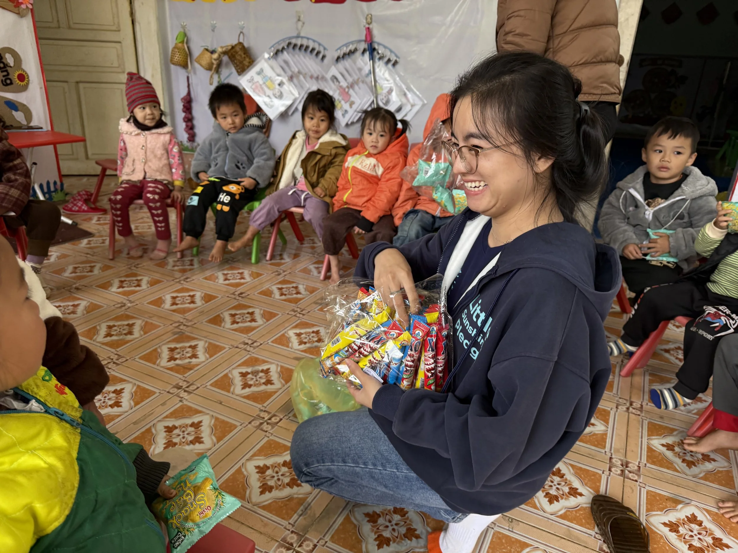 Little Sunshine Pledge volunteer handing out gift bags to children at an orphanage in Vietnam