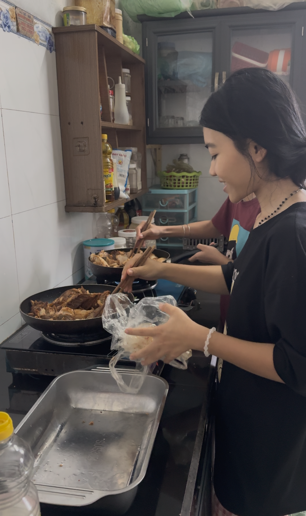 2 girls cooking on a portable stove in small frying pans while being happy, food visible to be cooking