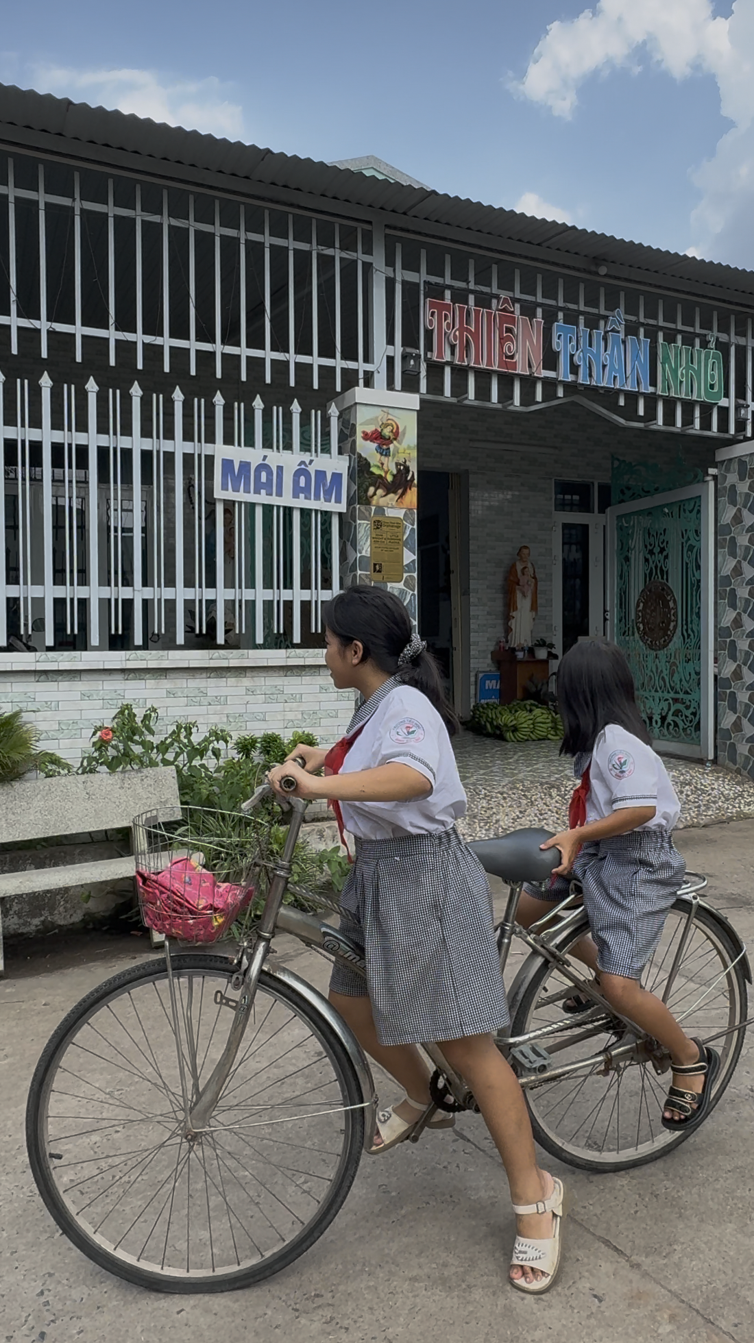 2 girls one bigger one smaller are getting on a single bike to ride to school