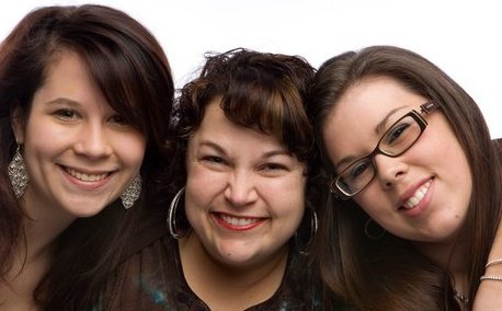 Three women smiling close together for a photo.