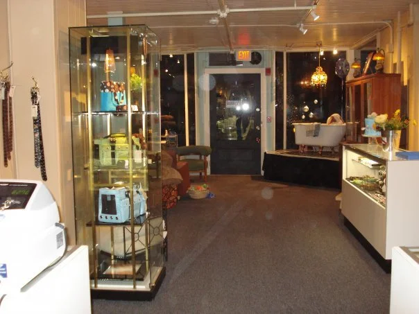 Interior of a boutique or jewelry store with display cases, a white footed bathtub, and decorative chandelier lighting