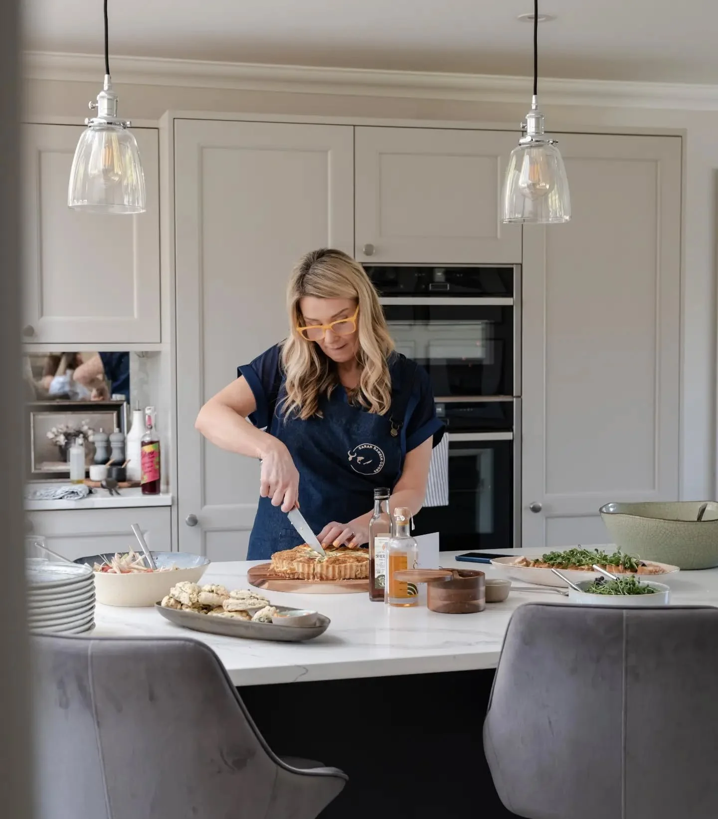 Sarah Rankin chef cutting bread in kitchen on marble island