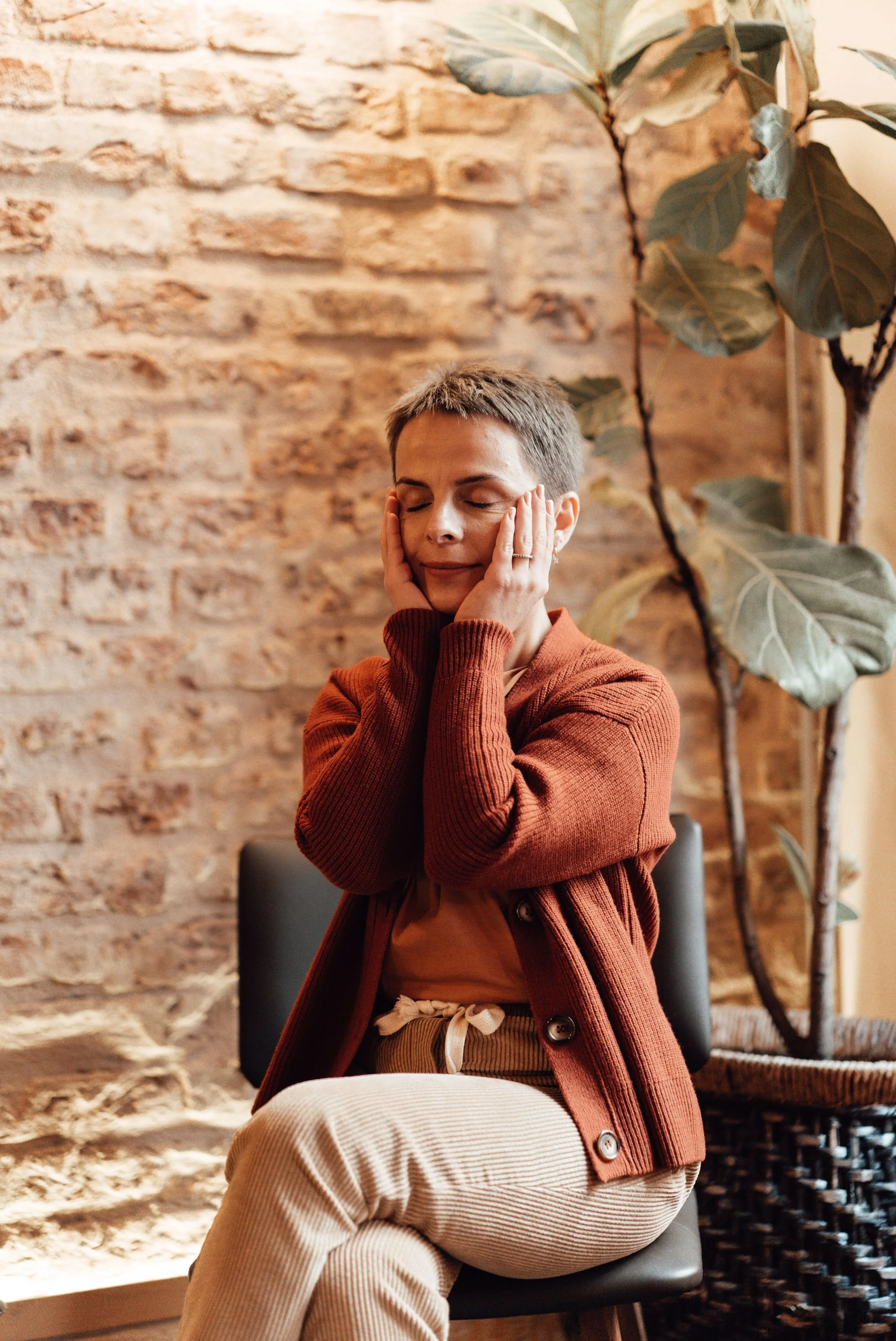 Woman with eyes closed, hands gently resting on her jaw, feeling calm and relieved