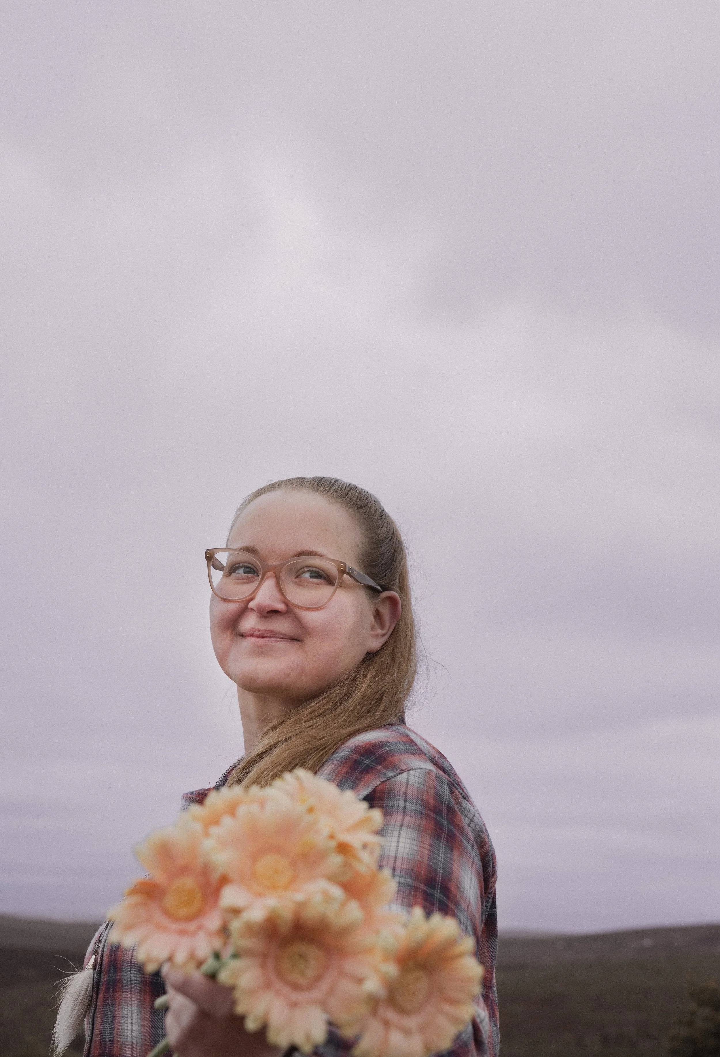 SEO-asiantuntija Sarita Peltoniemi hymyilee kameralle kukkien kanssa.