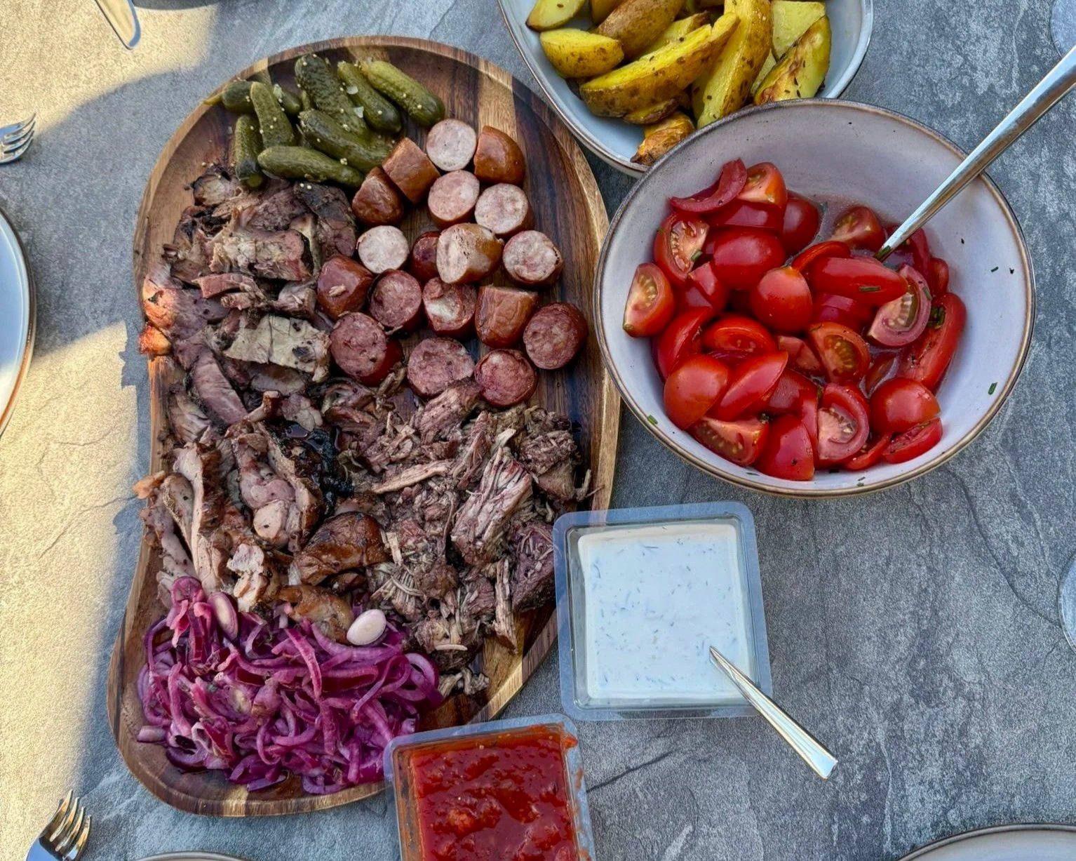 grillattua lihaa lautasella tomaattien ja perunoiden kera