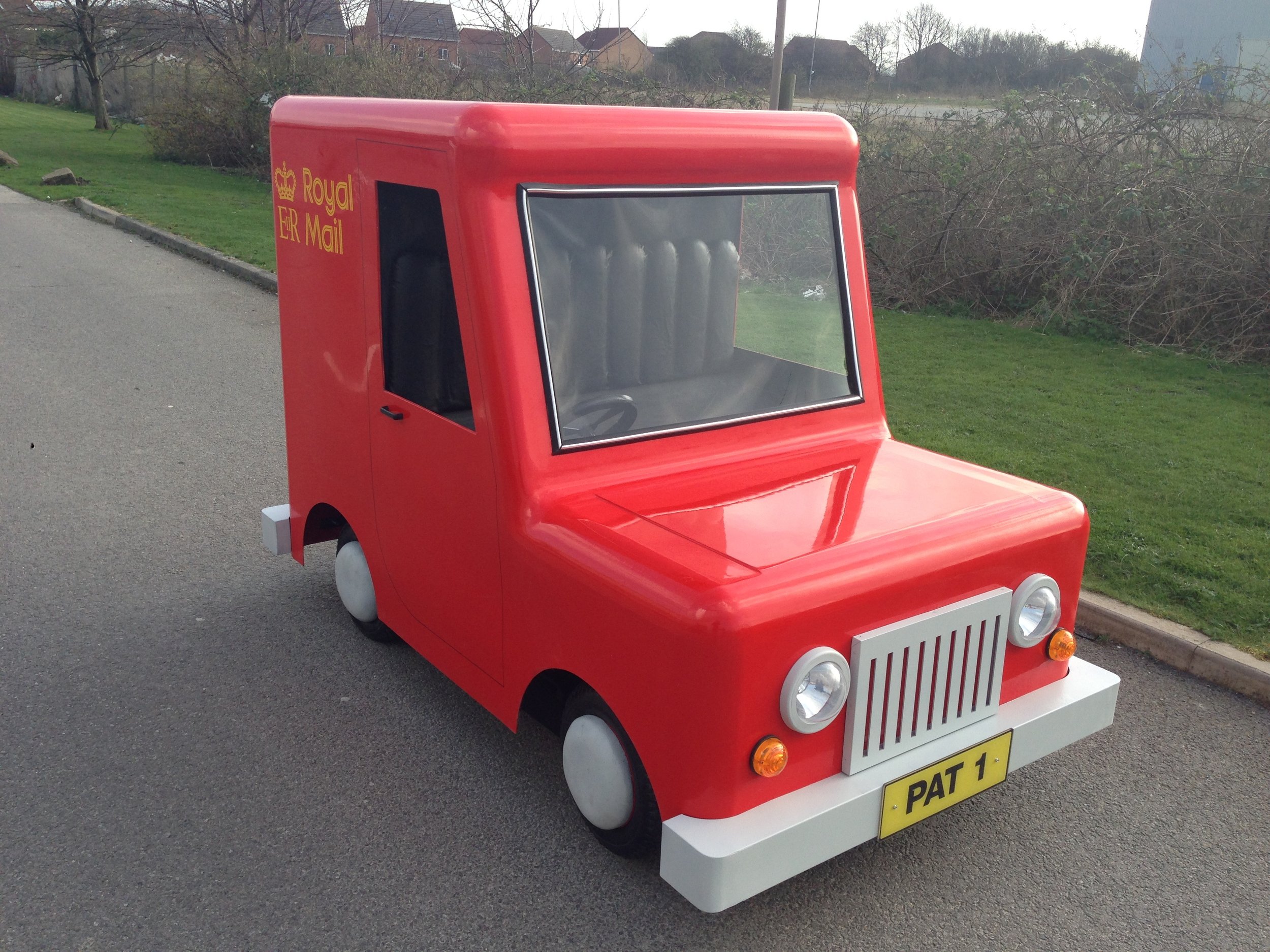 Small red vehicle resembling a post van, marked with "Royal Mail."