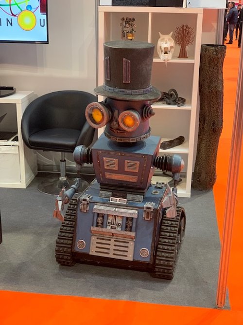 Steampunk robot with top hat on display in exhibition booth.