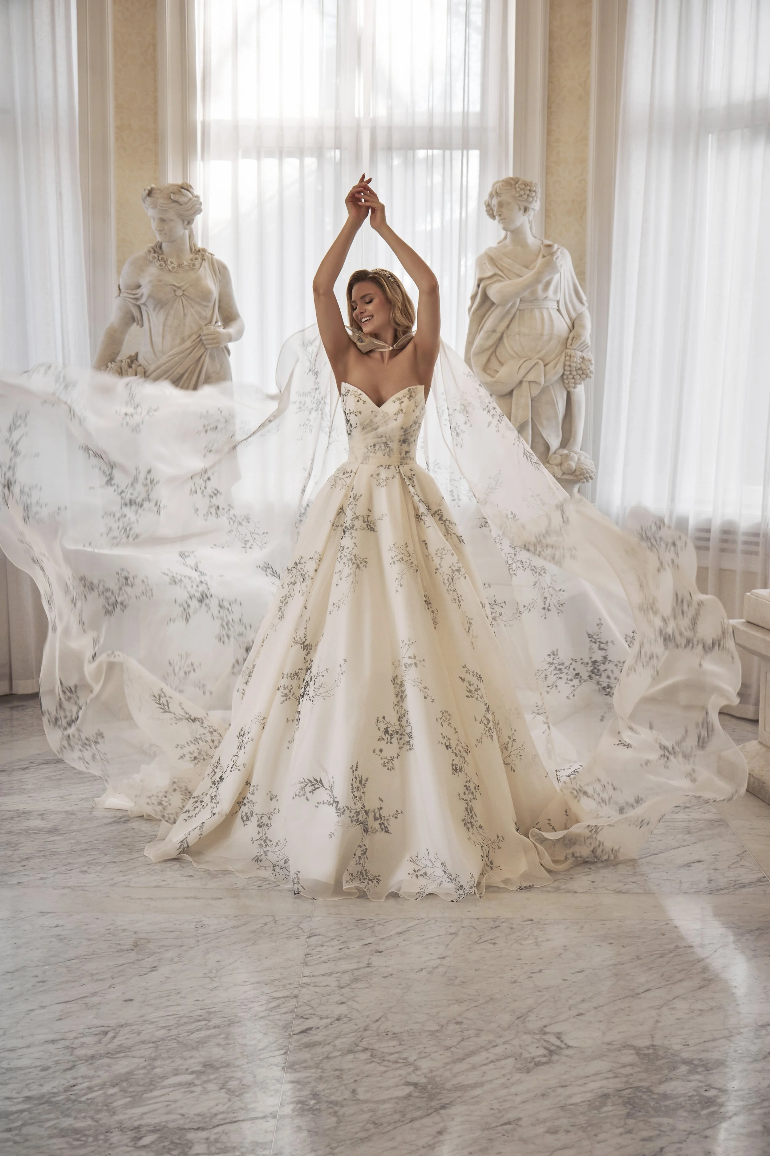 Full front view of Lia Bella Model Therese, a botanical-print ball gown wedding dress with a dramatic detachable cape.