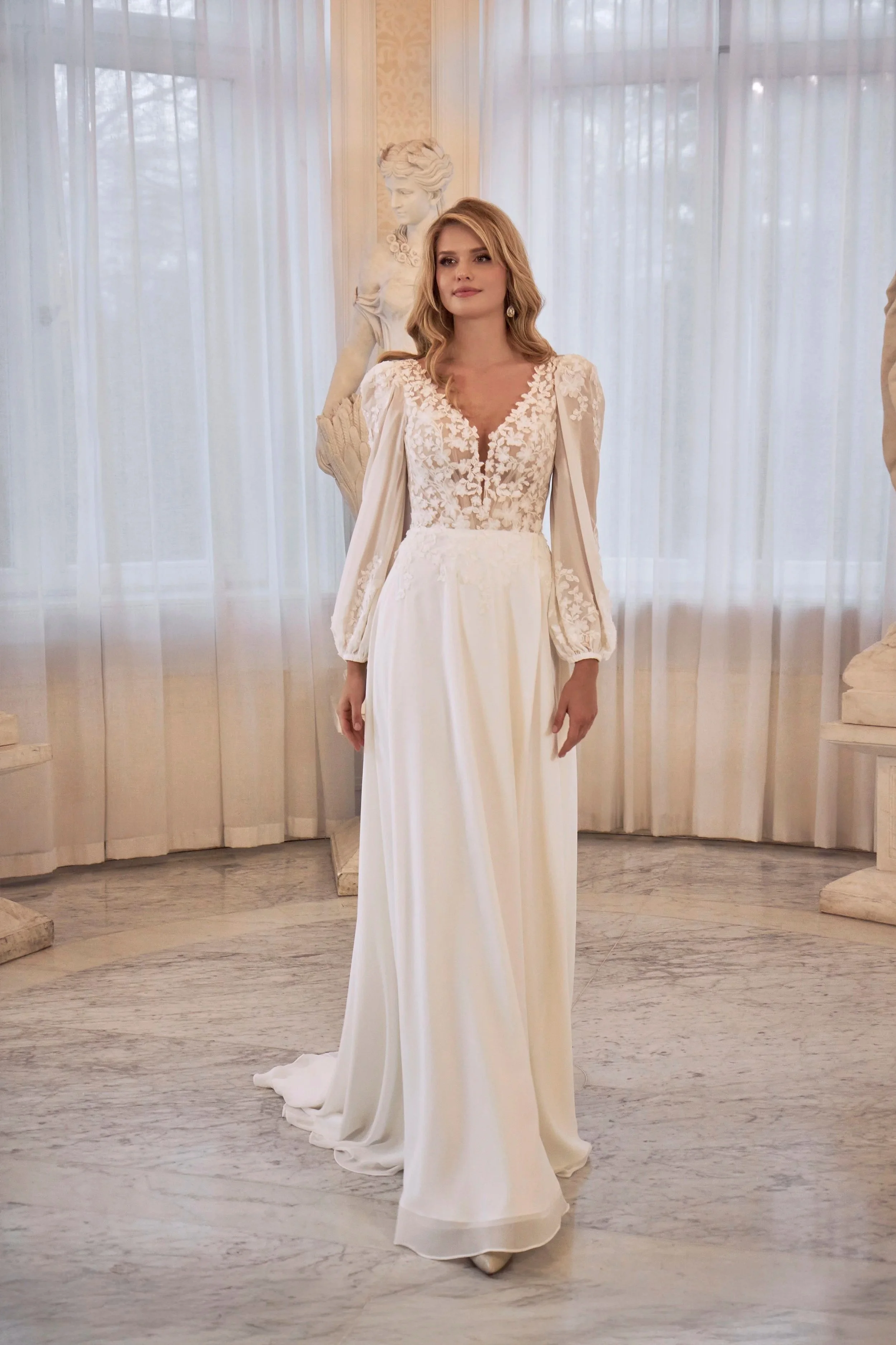Full front view of Lia Bella Model Tiliane, a flowing A-line wedding dress with a floral lace bodice and sheer bishop sleeves.