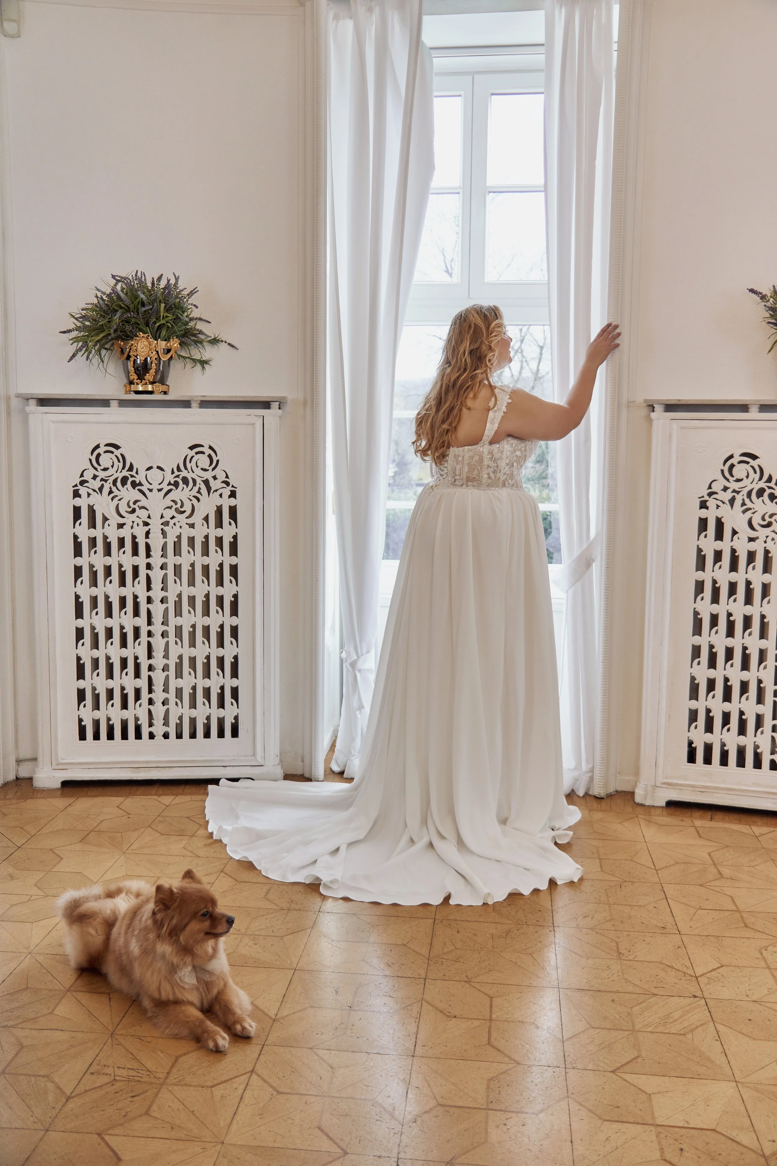 Back view of Lia Bella Model Tibby Curvy showing the illusion lace bodice, covered buttons and flowing chiffon chapel train.