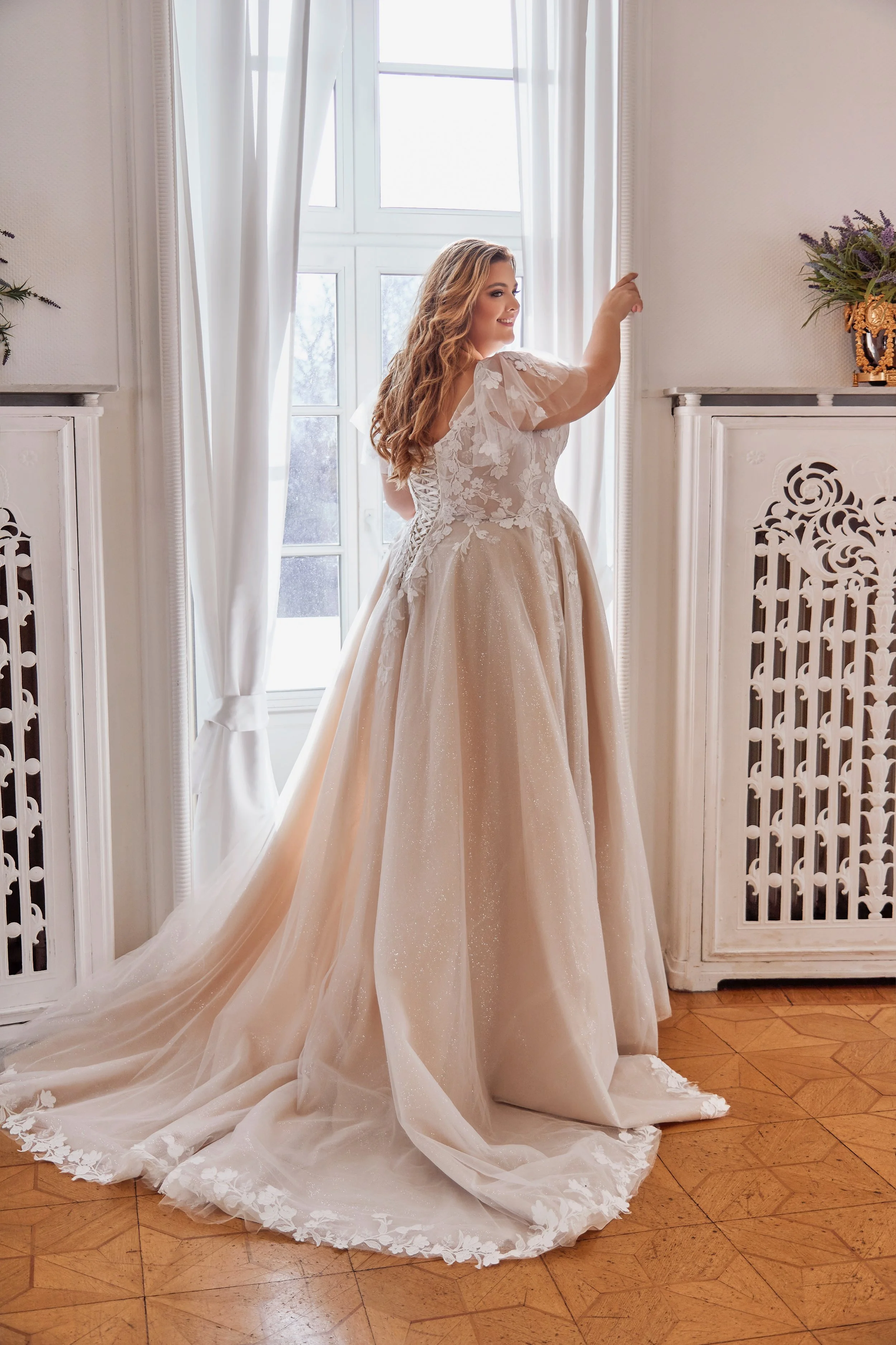 Rear view of Lia Bella Tsuna featuring a lace-up corset back and a sweeping glitter tulle train edged with floral appliqués.