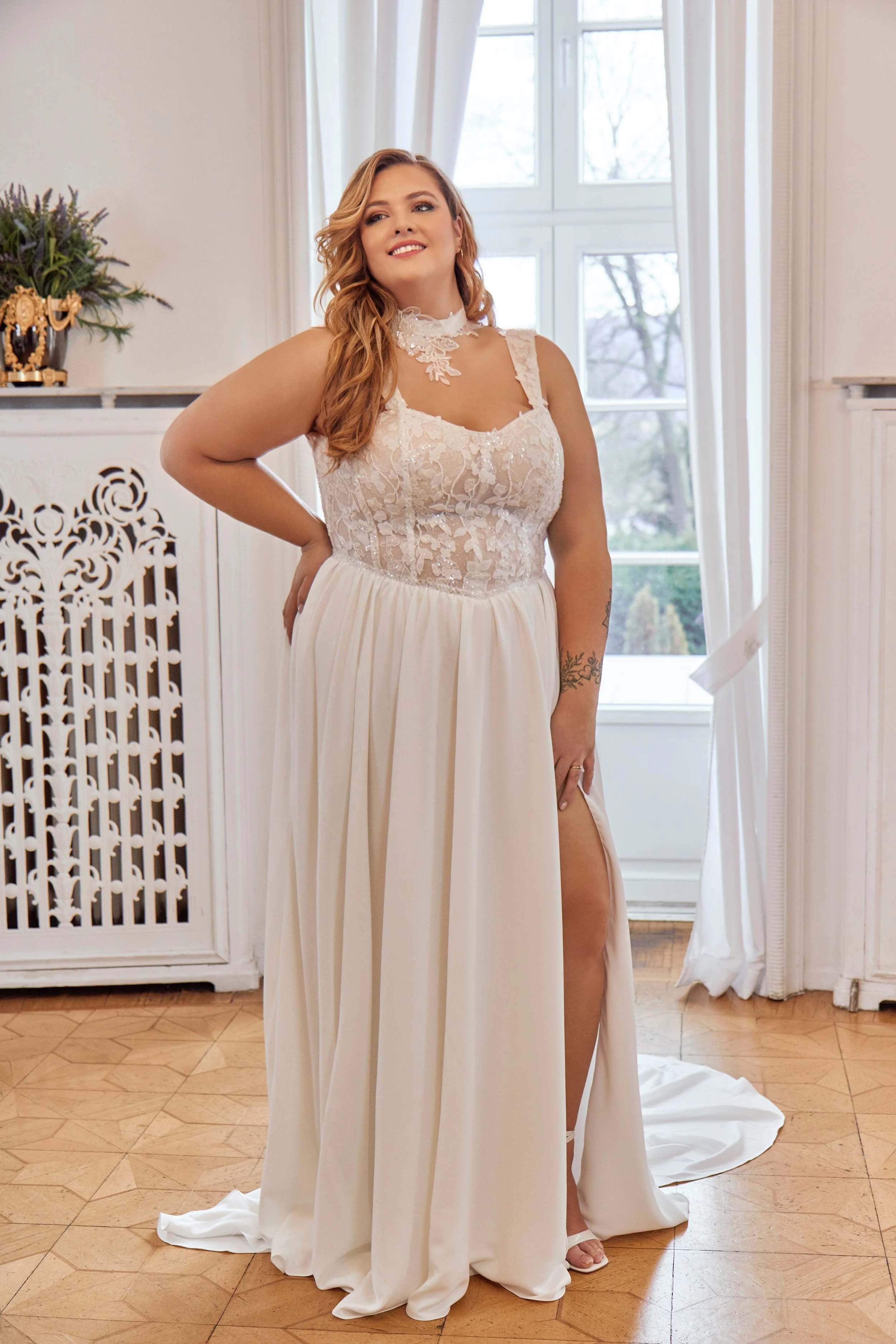 Full front view of Lia Bella Model Tibby Curvy, a lace and chiffon A-line wedding dress with wide straps and a high skirt slit.