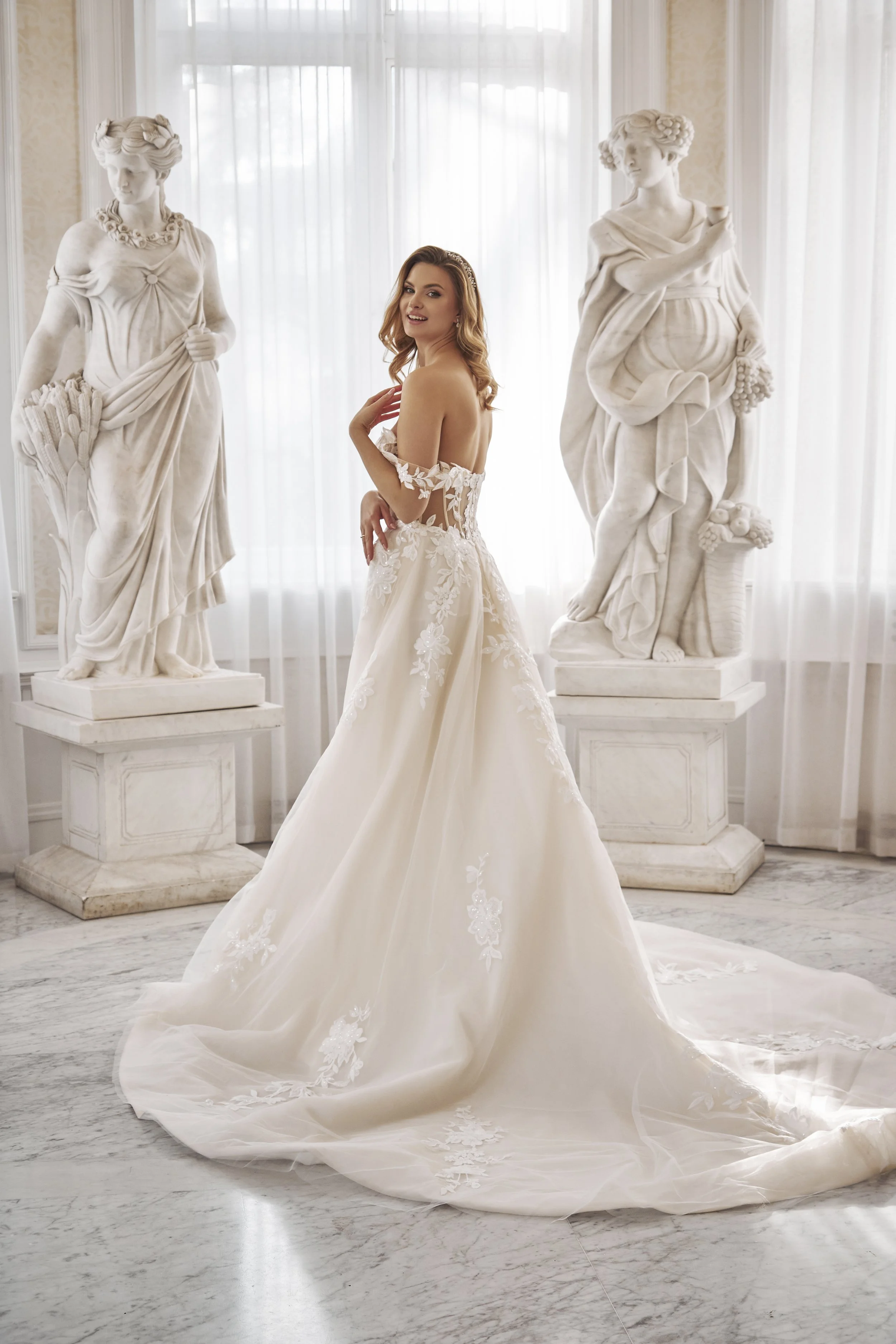 Back view of Lia Bella Model Tamse showing the voluminous ball gown skirt and expansive lace-appliquéd train.