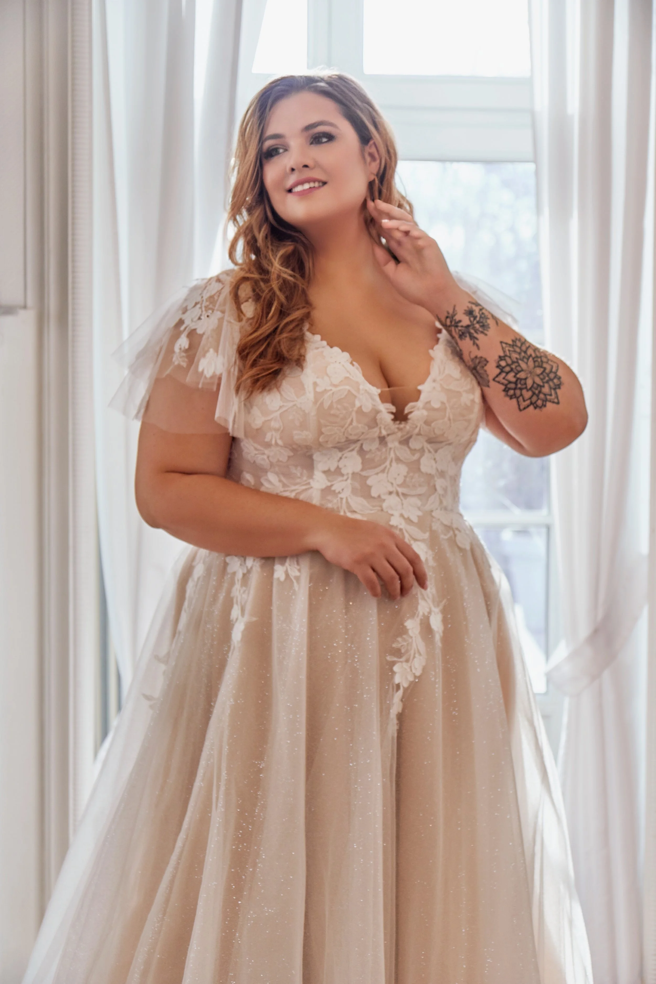 Close view of the floral lace bodice, plunging V-neckline and sheer flutter sleeves of Lia Bella wedding dress Tsuna.