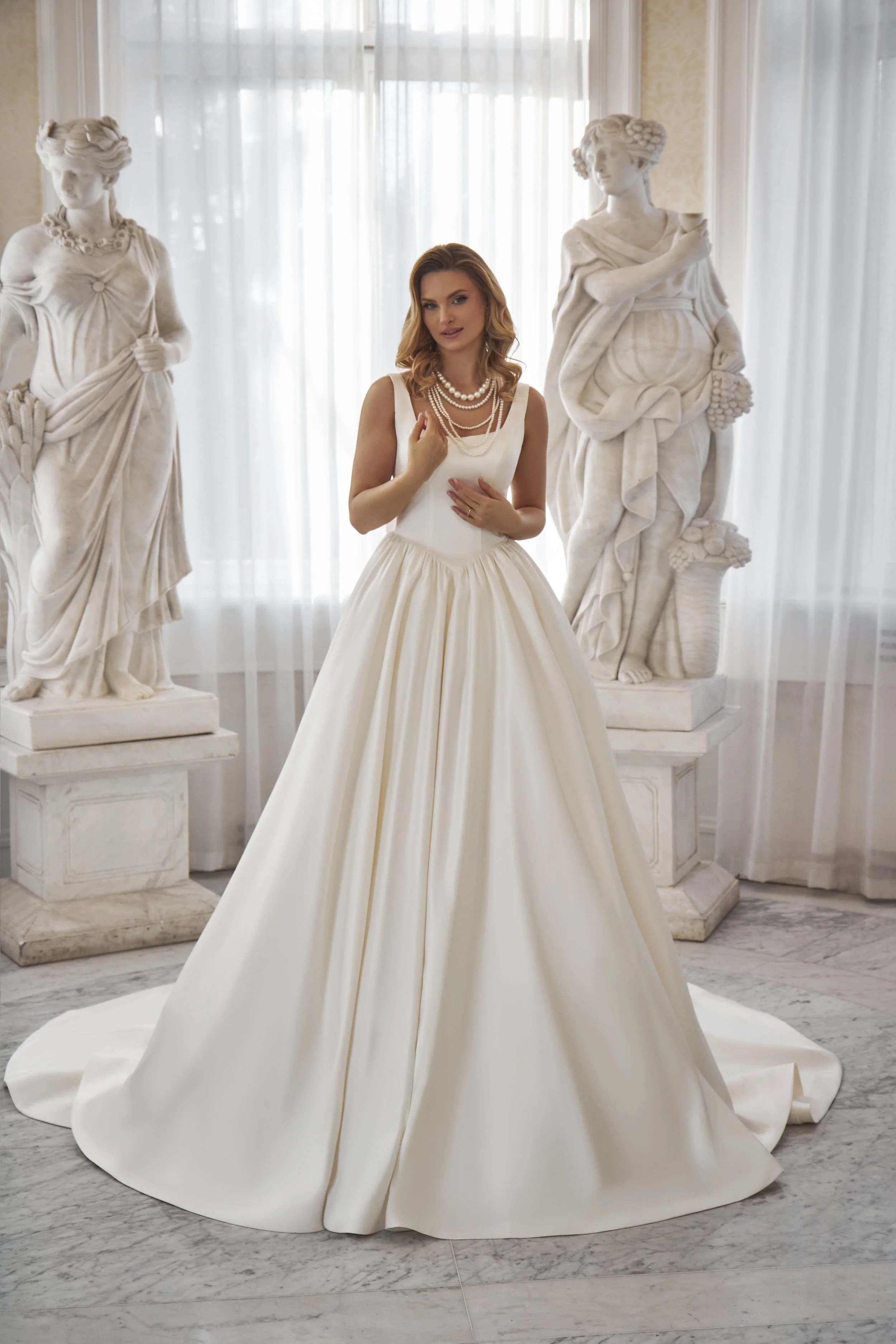 Full front view of Lia Bella Model Toshi, a minimalist satin ball gown with a scoop neckline and deeply pointed basque waist.