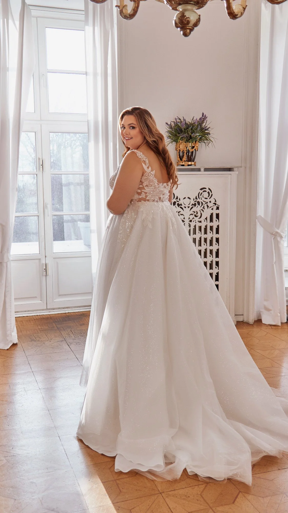Back view of Lia Bella Model Trudy showing the low illusion lace back and softly shimmering glitter-tulle A-line skirt.