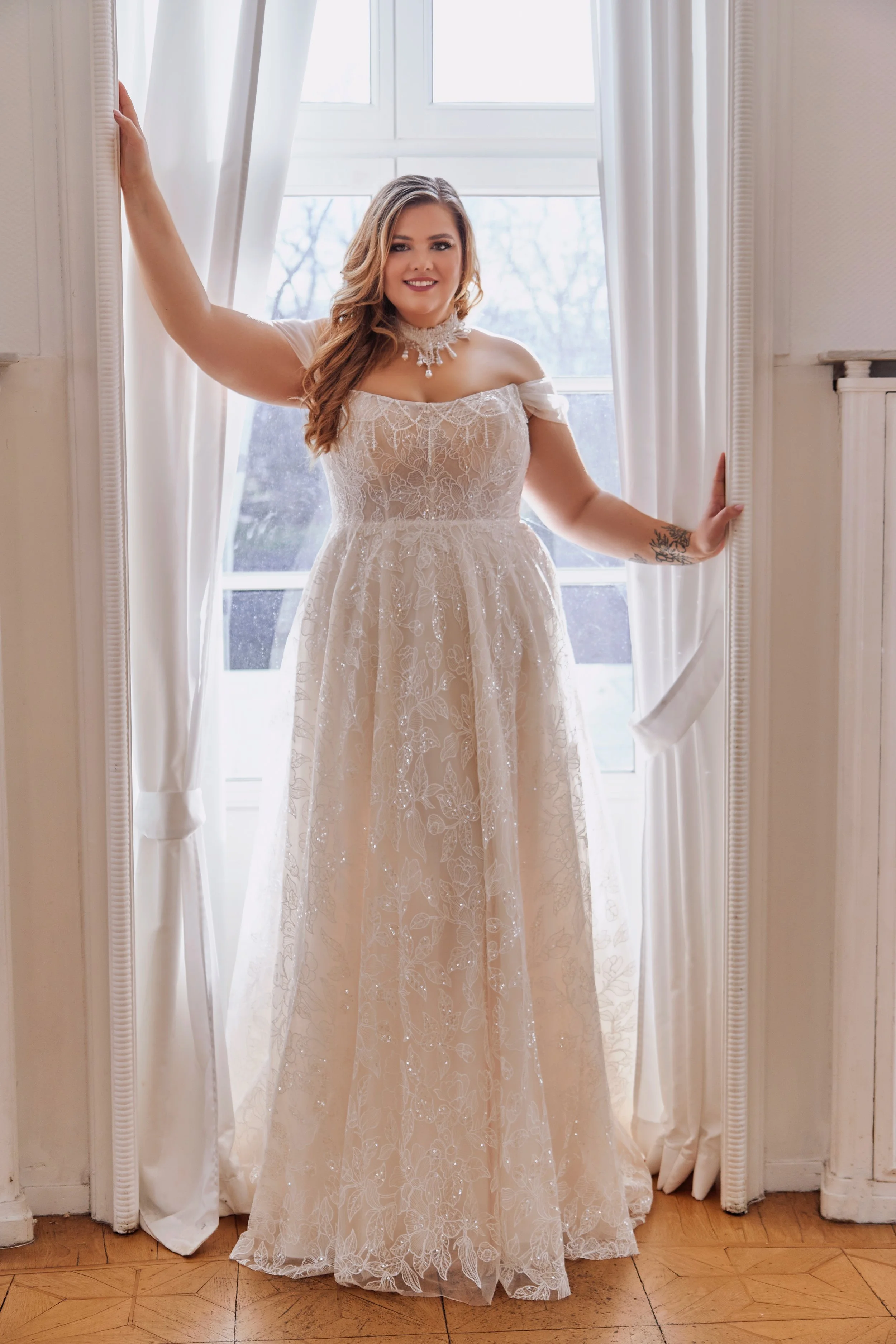 Full front view of Lia Bella Model Temea, a curvy A-line wedding dress with embroidered lace and soft off-the-shoulder tulle straps.