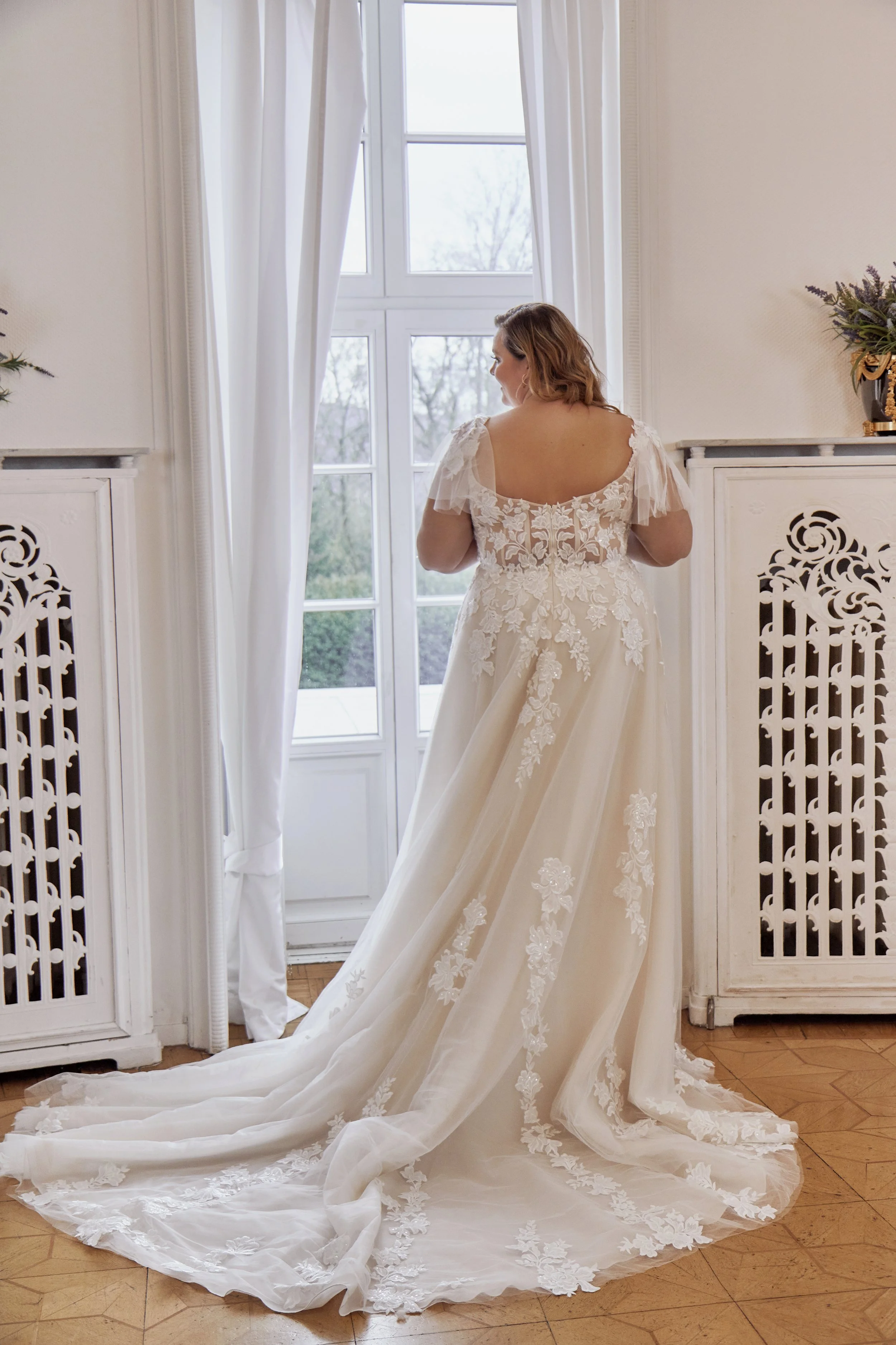 Full back view of Lia Bella Model Tasia highlighting the sheer floral lace back and lace-trimmed chapel train.