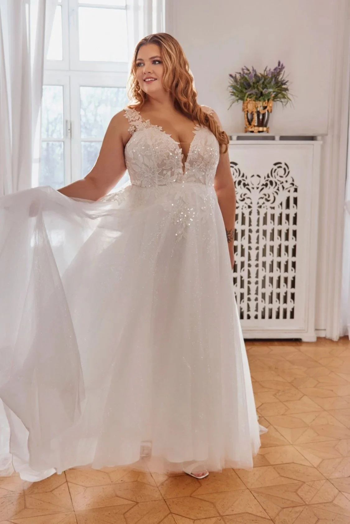 Three-quarter front view of Lia Bella Model Trudy displaying the flowing glitter-tulle skirt and cascading floral lace appliqués.