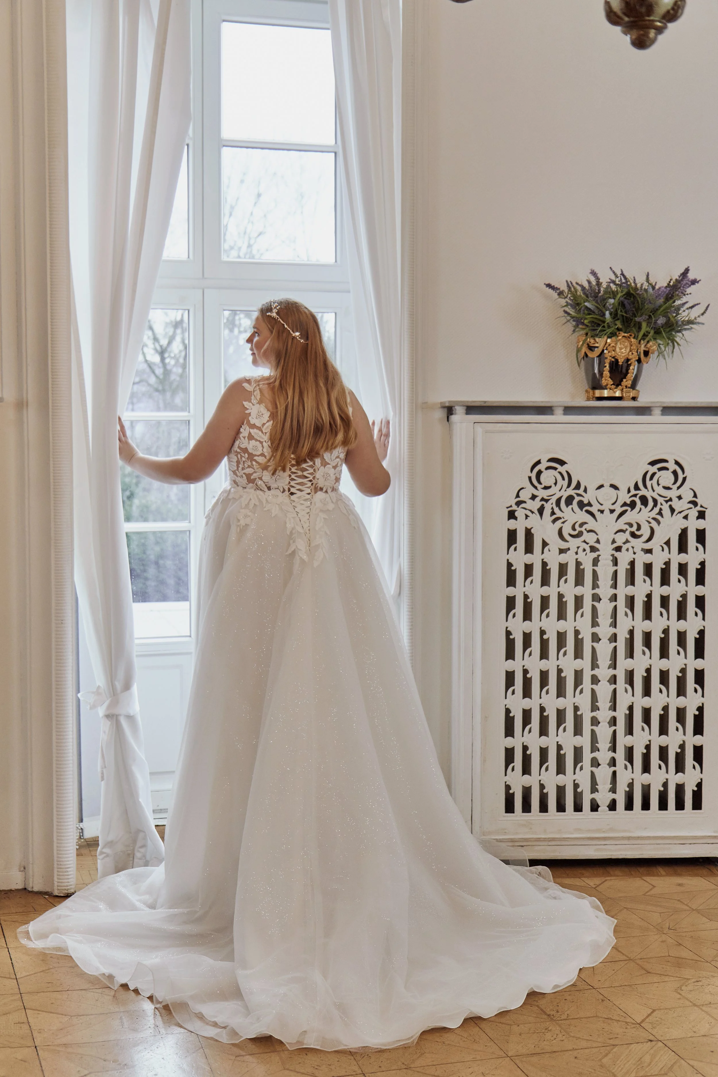Back view of Lia Bella Model Tovi featuring an illusion lace bodice, corset lacing and a flowing glitter-tulle chapel train.