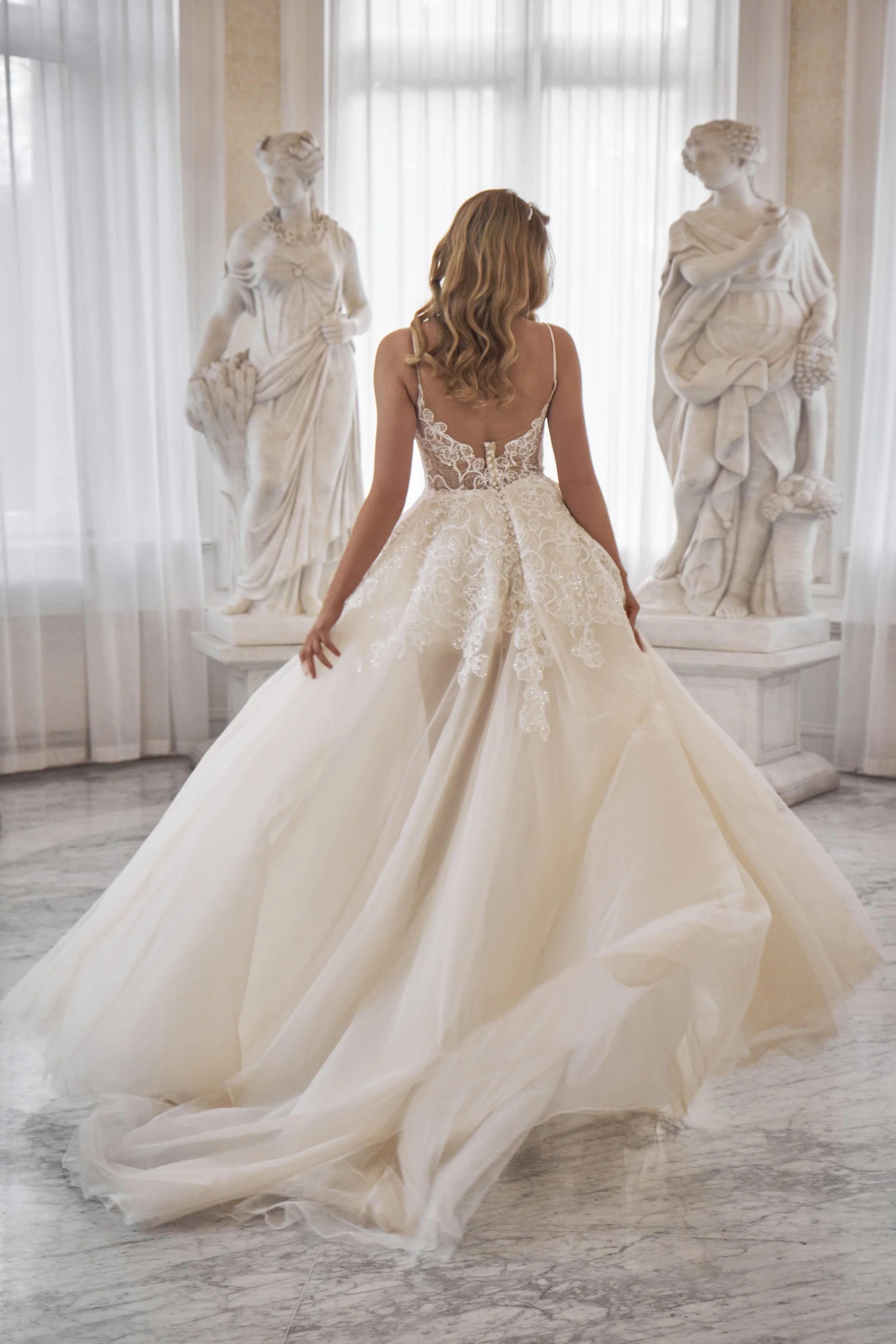 Back view of Lia Bella Model Teresa showing the low illusion back, covered buttons and layered chapel train.
