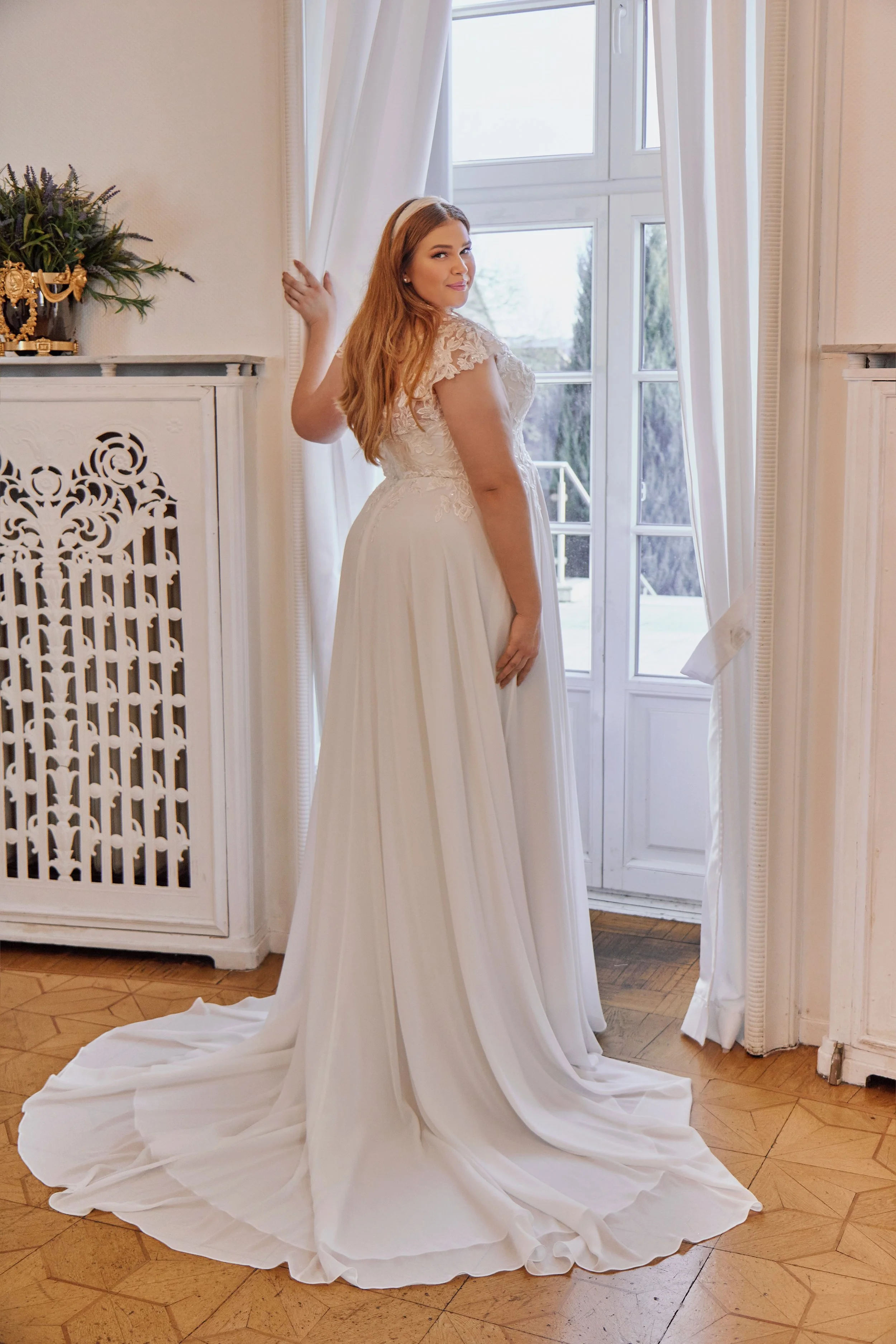 Back view of Lia Bella Model Trixie showing the illusion lace bodice and wide flowing chiffon chapel train.