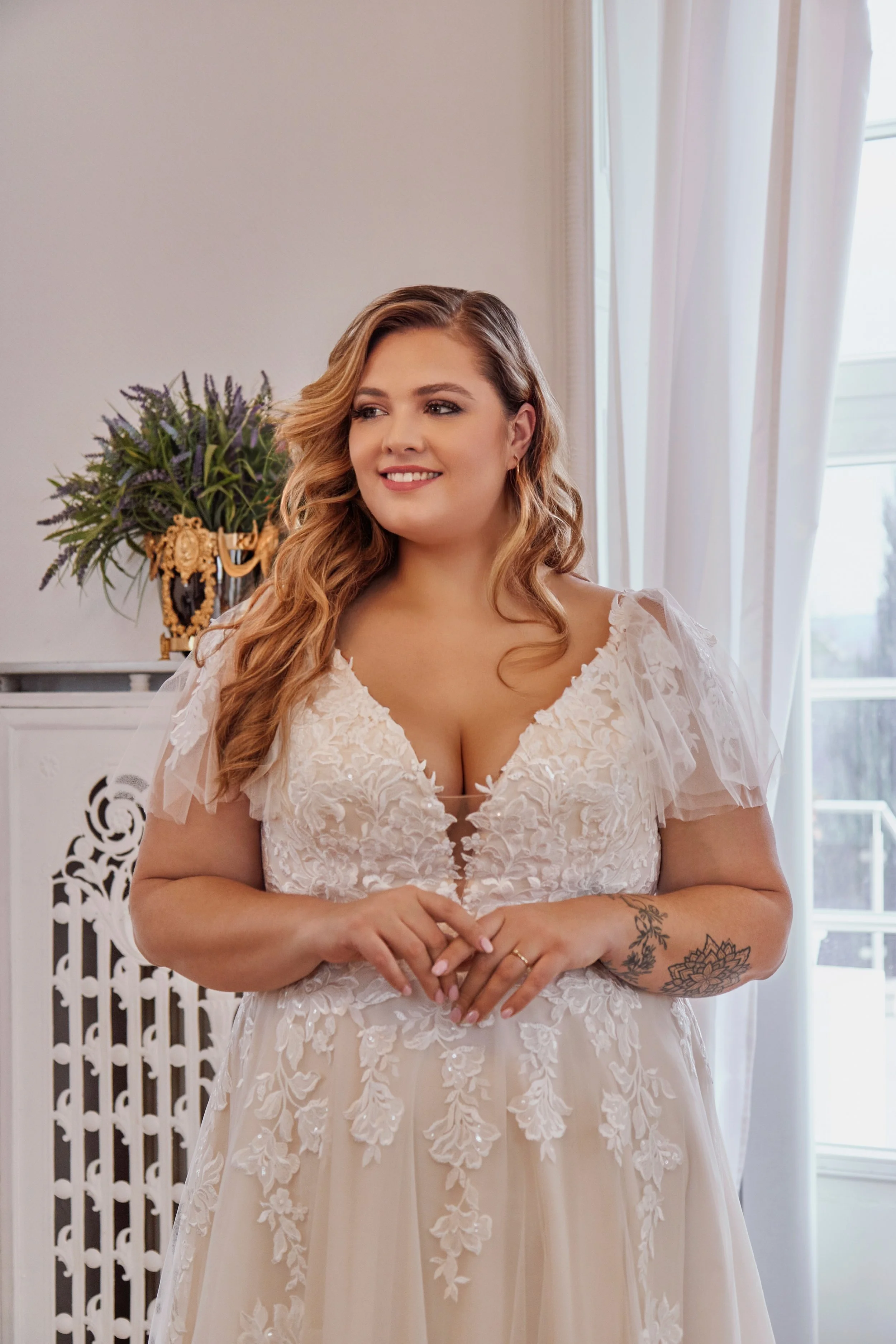 Close-up of Lia Bella Model Tasia featuring a plunging illusion neckline, floral lace bodice and sheer flutter sleeves.