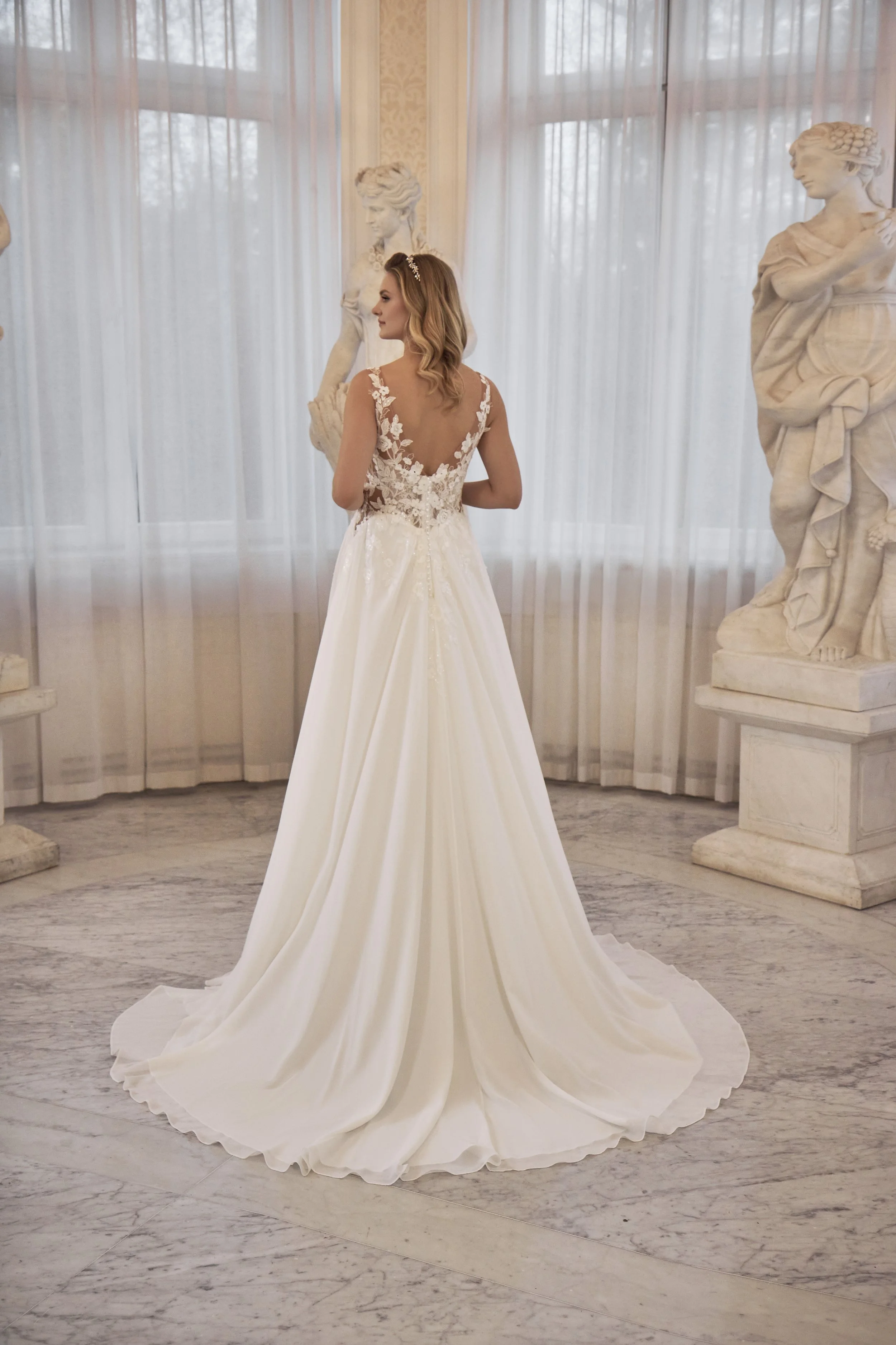 Full back view of Lia Bella Model Timea showing the low V-back, floral lace detailing and flowing chapel train.