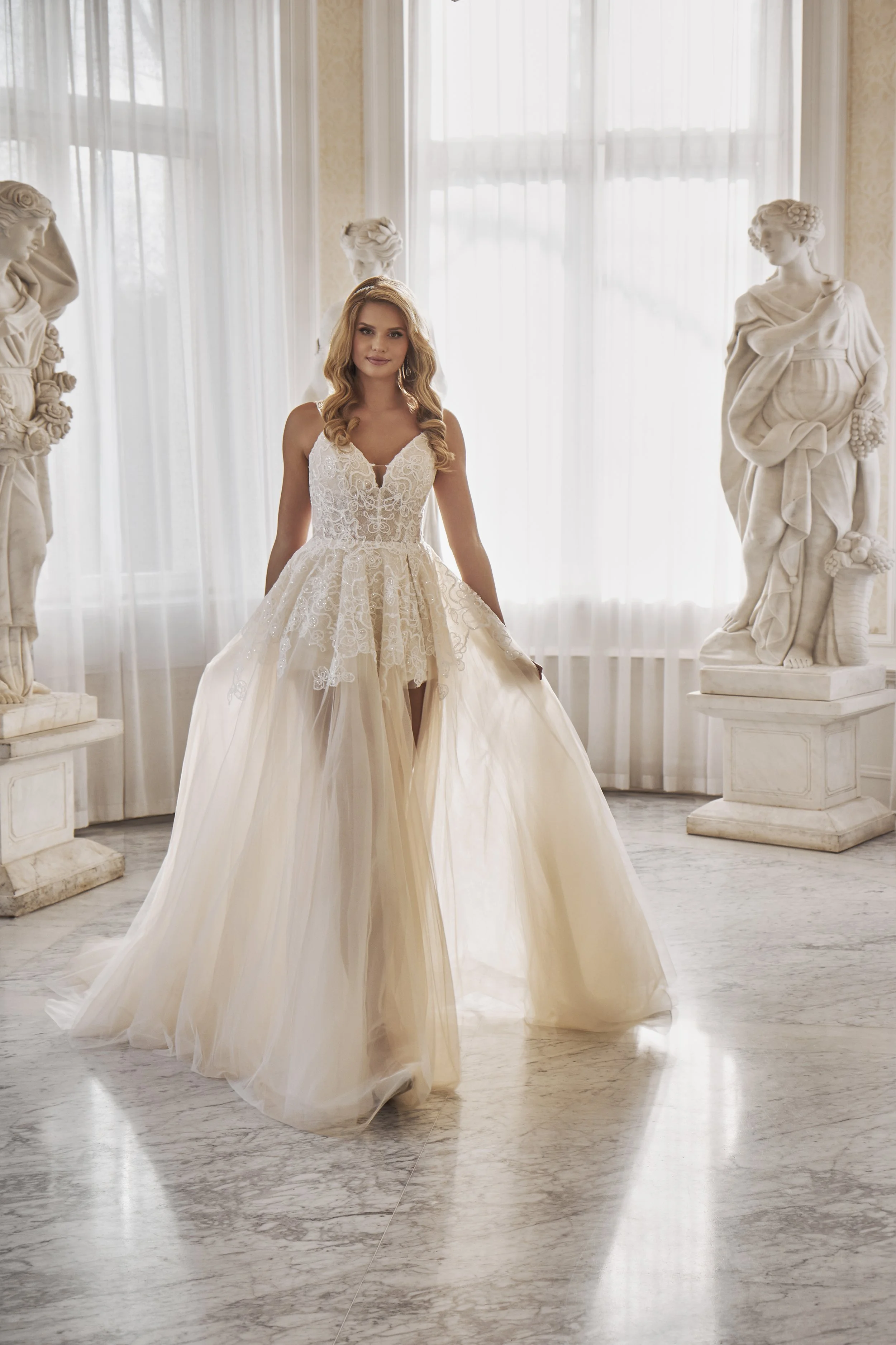 Full front view of Lia Bella Model Teresa, a high-low ball gown wedding dress with an open-front tulle skirt and lace underlayer.