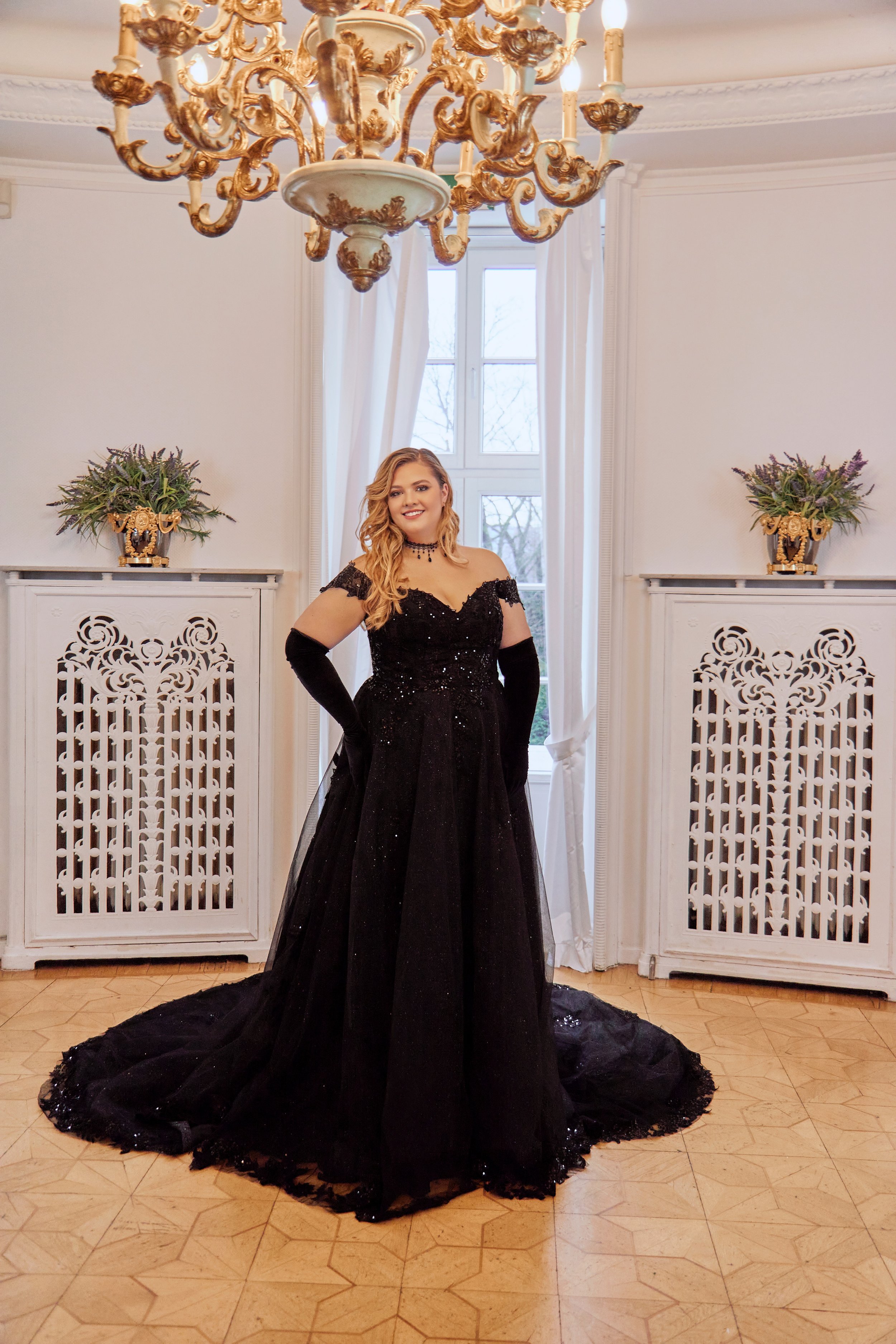 Full-length view of Lia Bella Model Tiana featuring an off-the-shoulder lace bodice, defined waist and black A-line skirt.