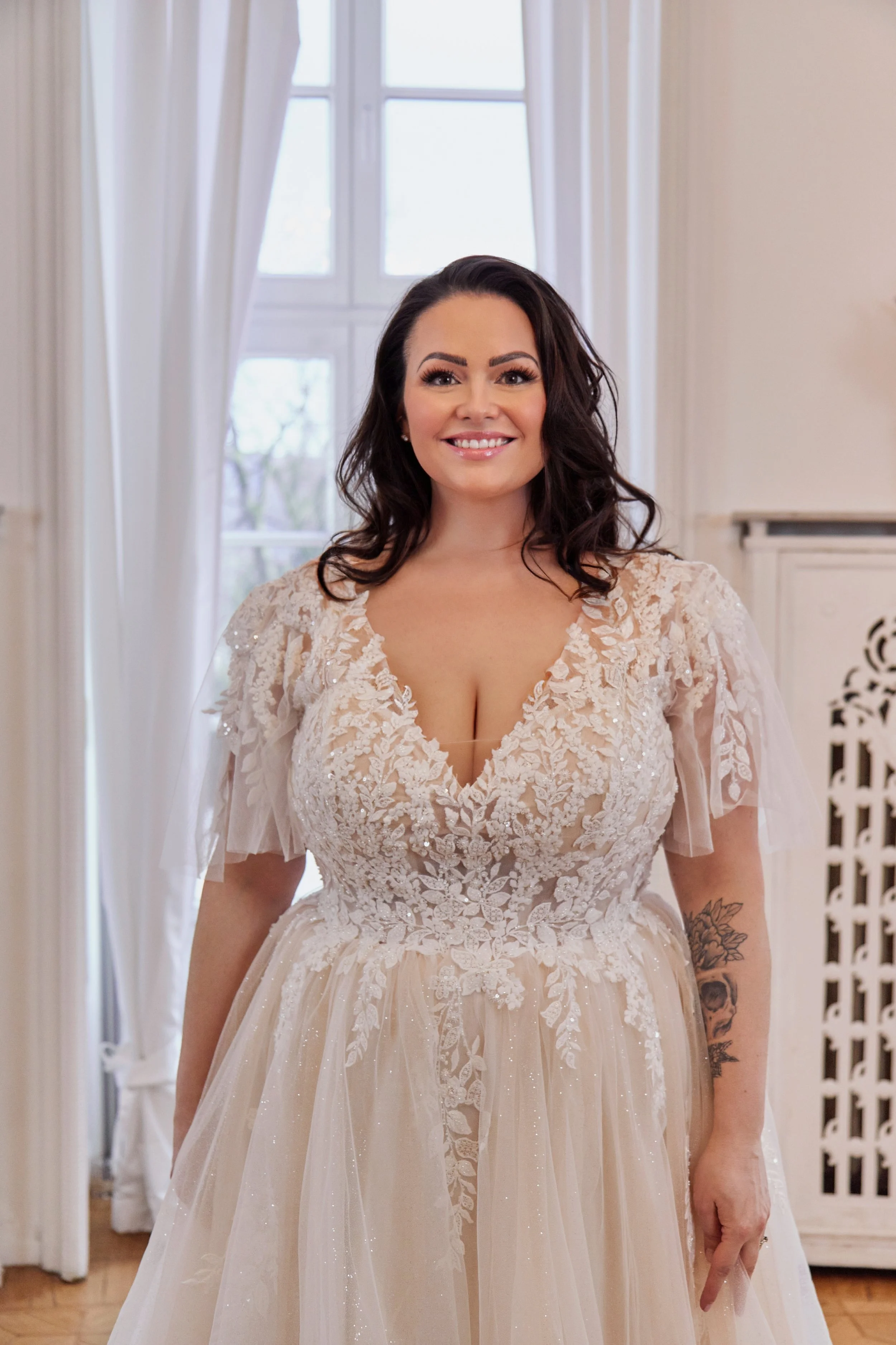 Close-up of Lia Bella Model Tamika featuring a plunging illusion neckline, floral lace bodice and sheer flutter sleeves.
