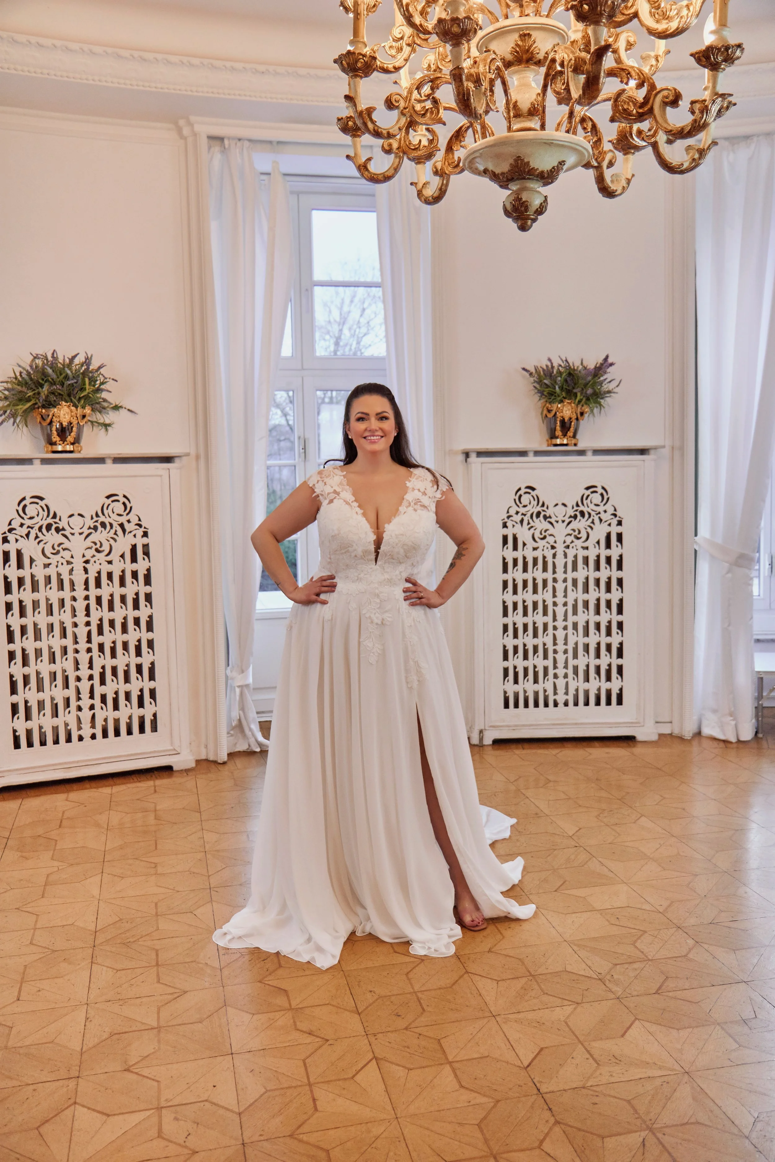 Wide full-length front view of Lia Bella Model Toya displaying the floral lace bodice, soft A-line silhouette and front slit.