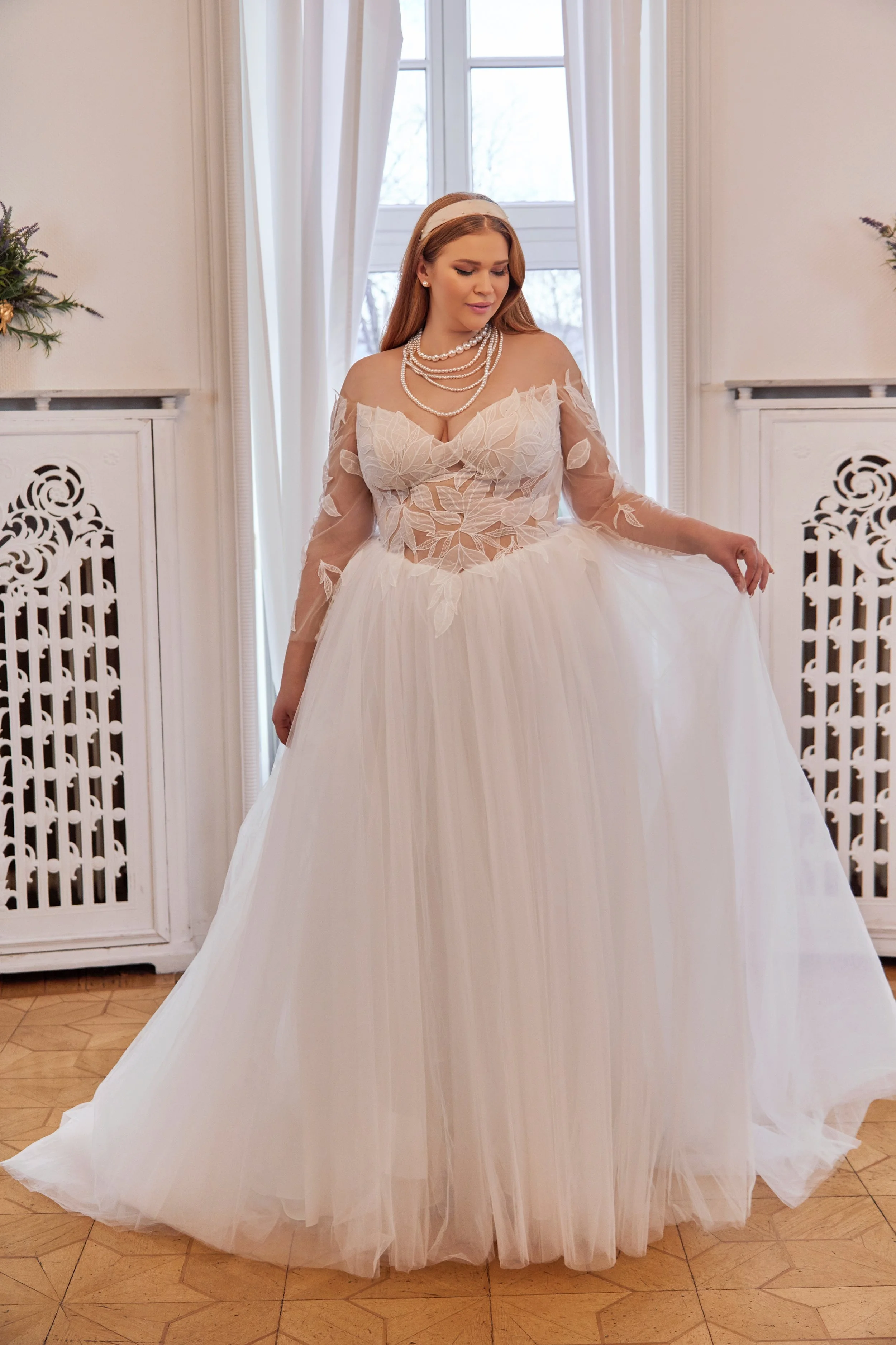 Full front view of Lia Bella Model Tessa, a curvy A-line wedding dress with a leaf lace illusion corset, three-quarter sleeves and flowing tulle skirt.