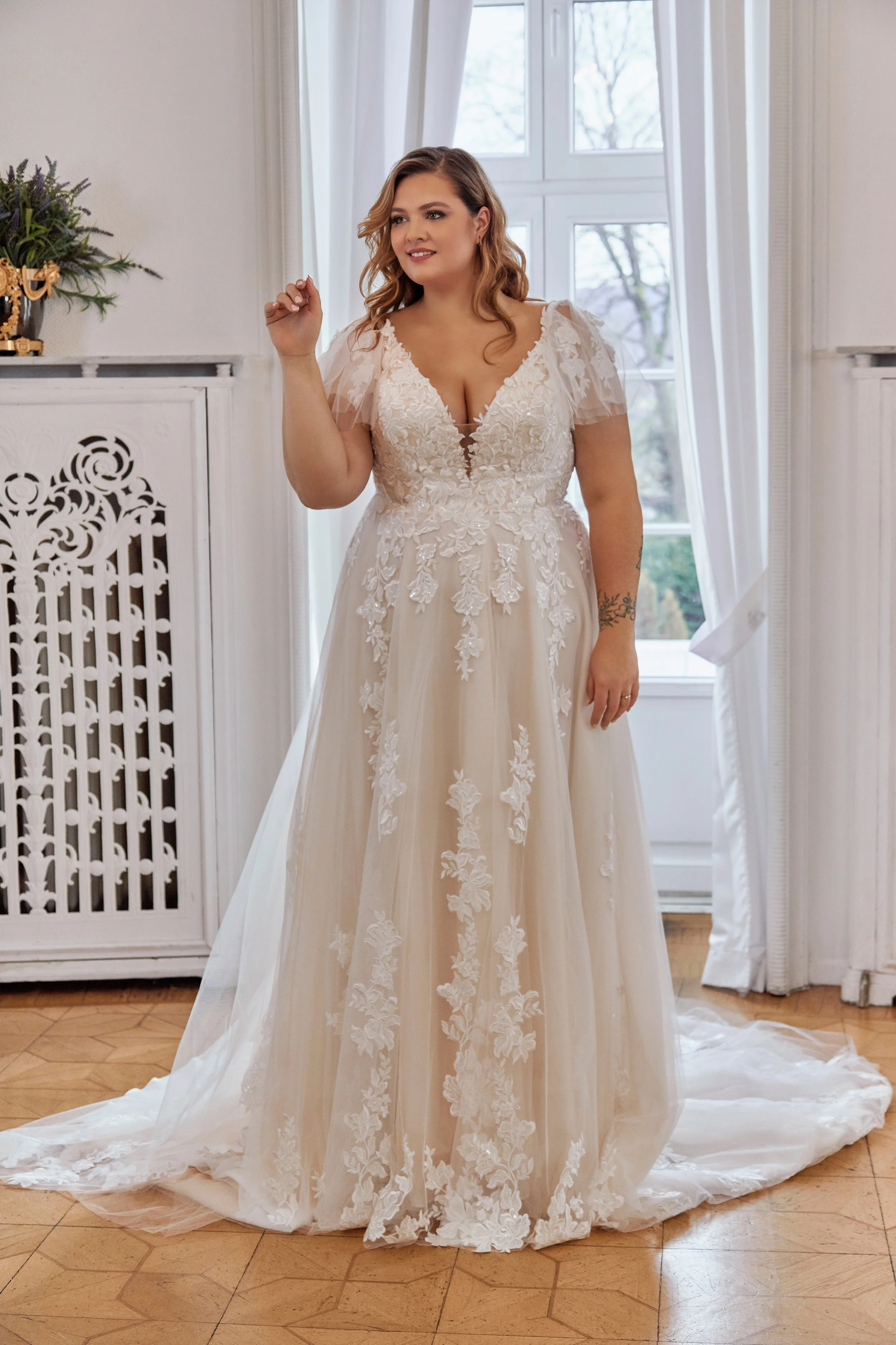 Full front view of Lia Bella Model Tasia, a curvy lace A-line wedding dress with flutter sleeves and a softly flowing tulle skirt.
