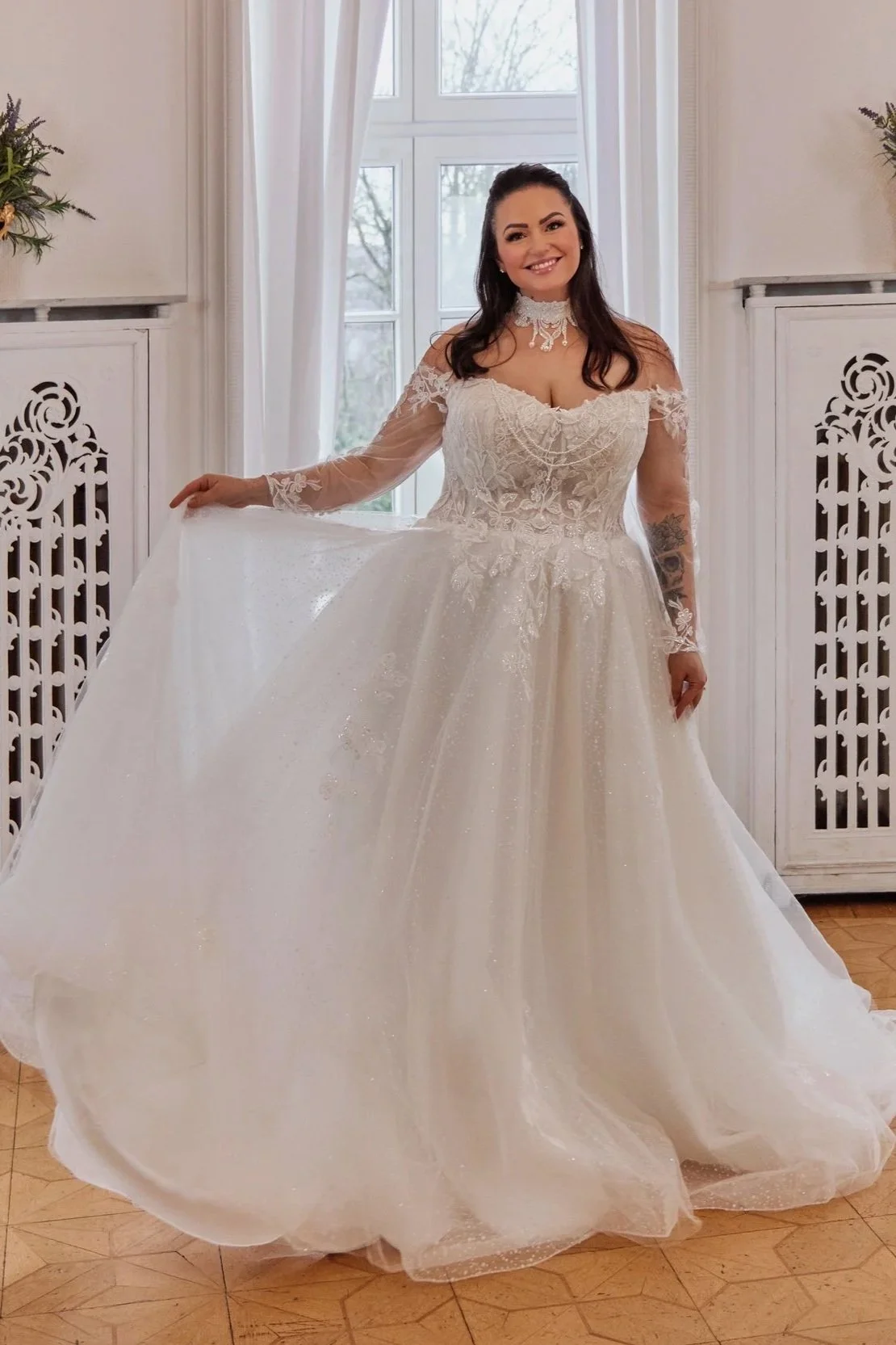 Wide full-length view of Lia Bella Model Tulla displaying the voluminous glitter-tulle skirt and off-the-shoulder lace sleeves.