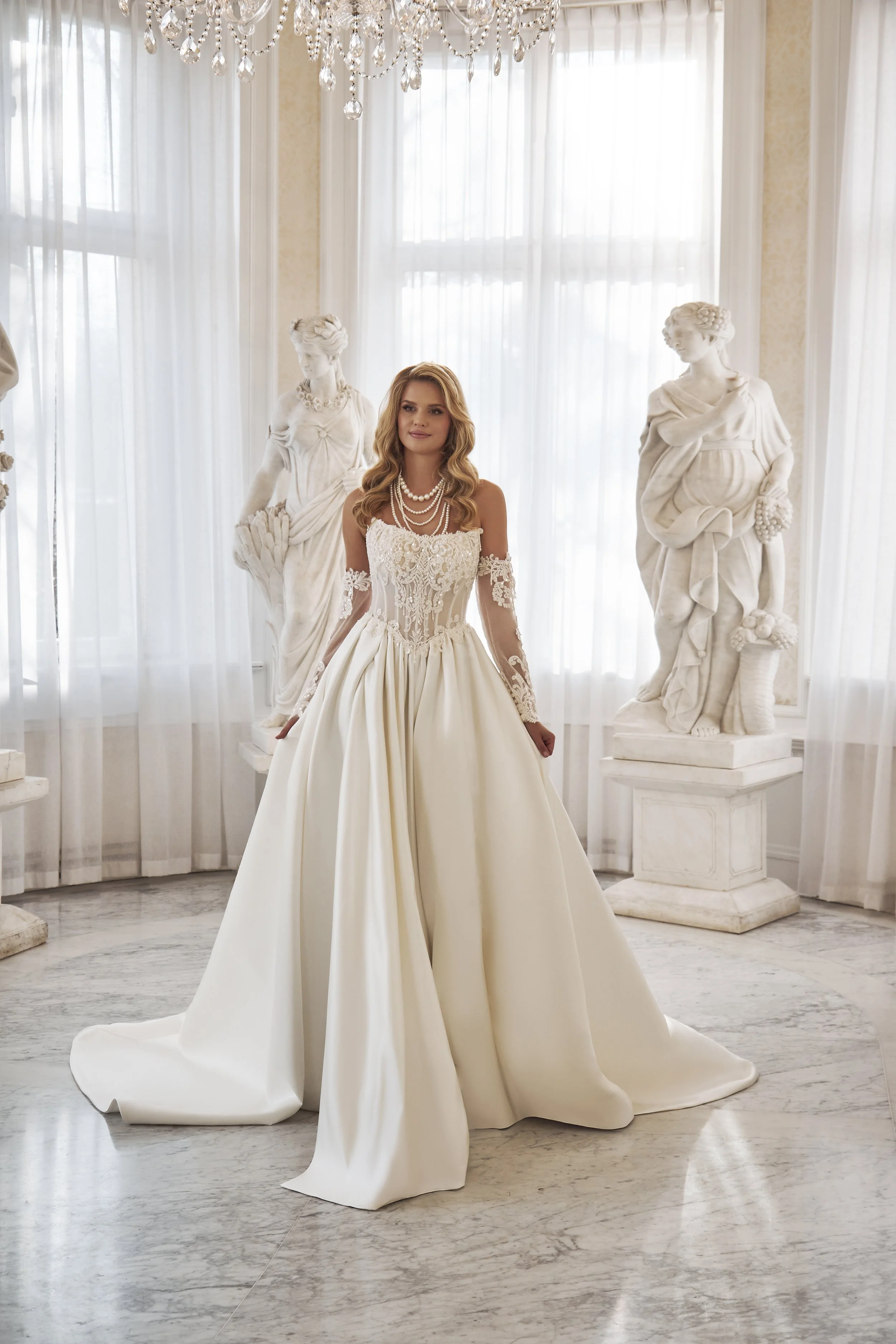 Full front view of Lia Bella Model Toell, a satin ball gown wedding dress with an embellished lace corset and off-the-shoulder sleeves.