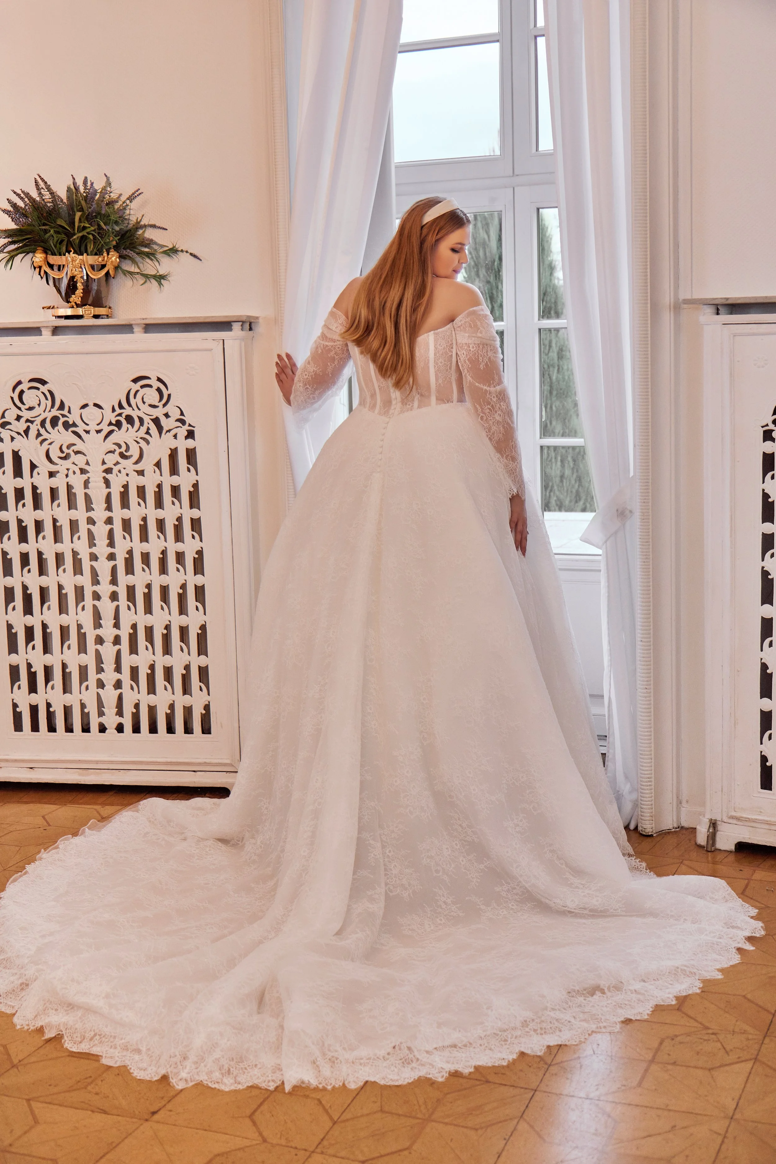 Full back view of Lia Bella Model Tia showing the illusion bodice, long lace sleeves, covered buttons and wide chapel train.