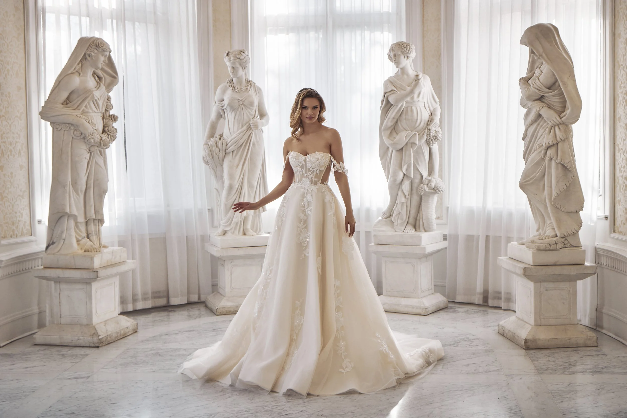 Bride wearing a strapless floral-lace A-line wedding dress surrounded by classical statues.