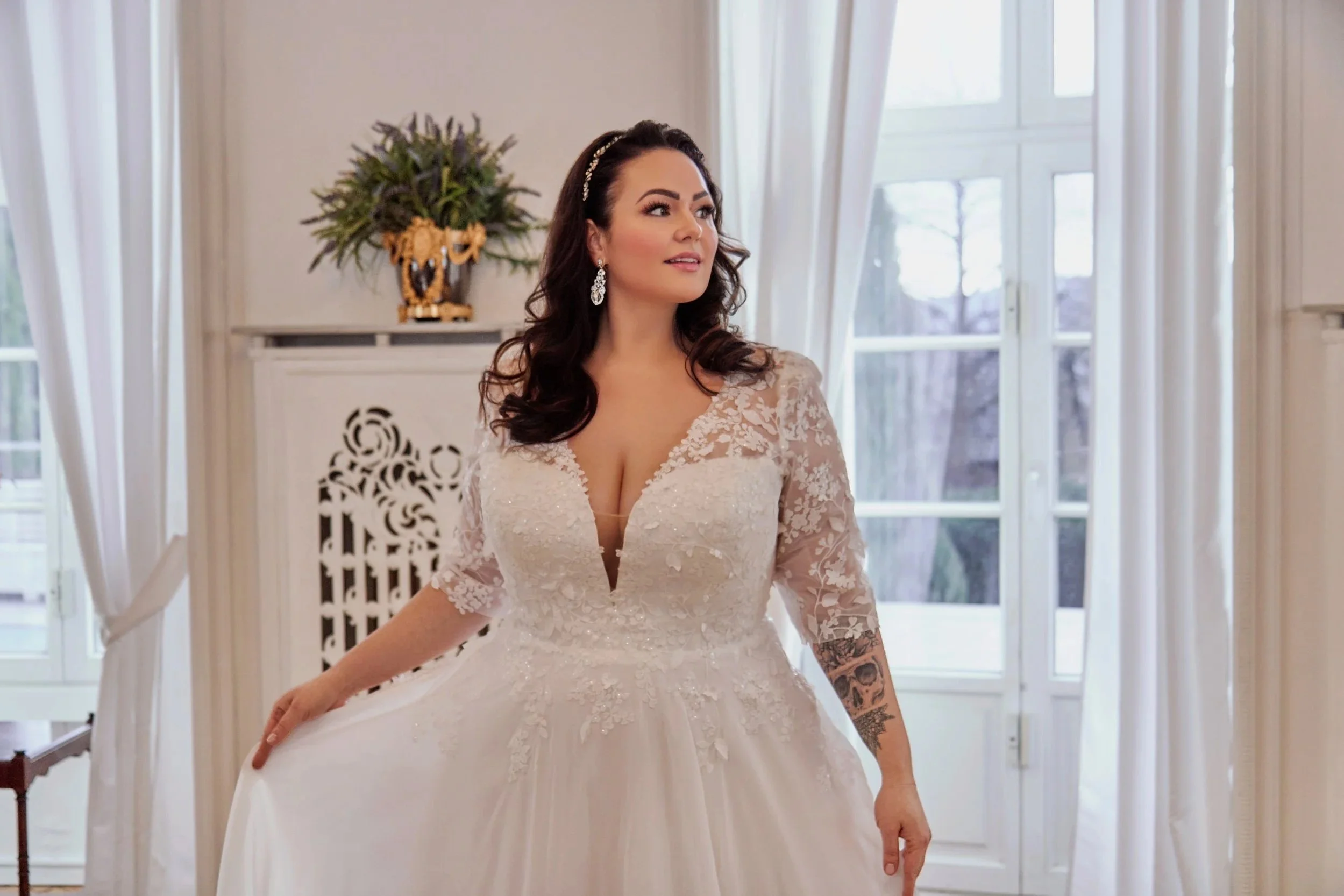 Curvy bride wearing an ivory lace Lia Bella wedding dress with a deep V-neckline.
