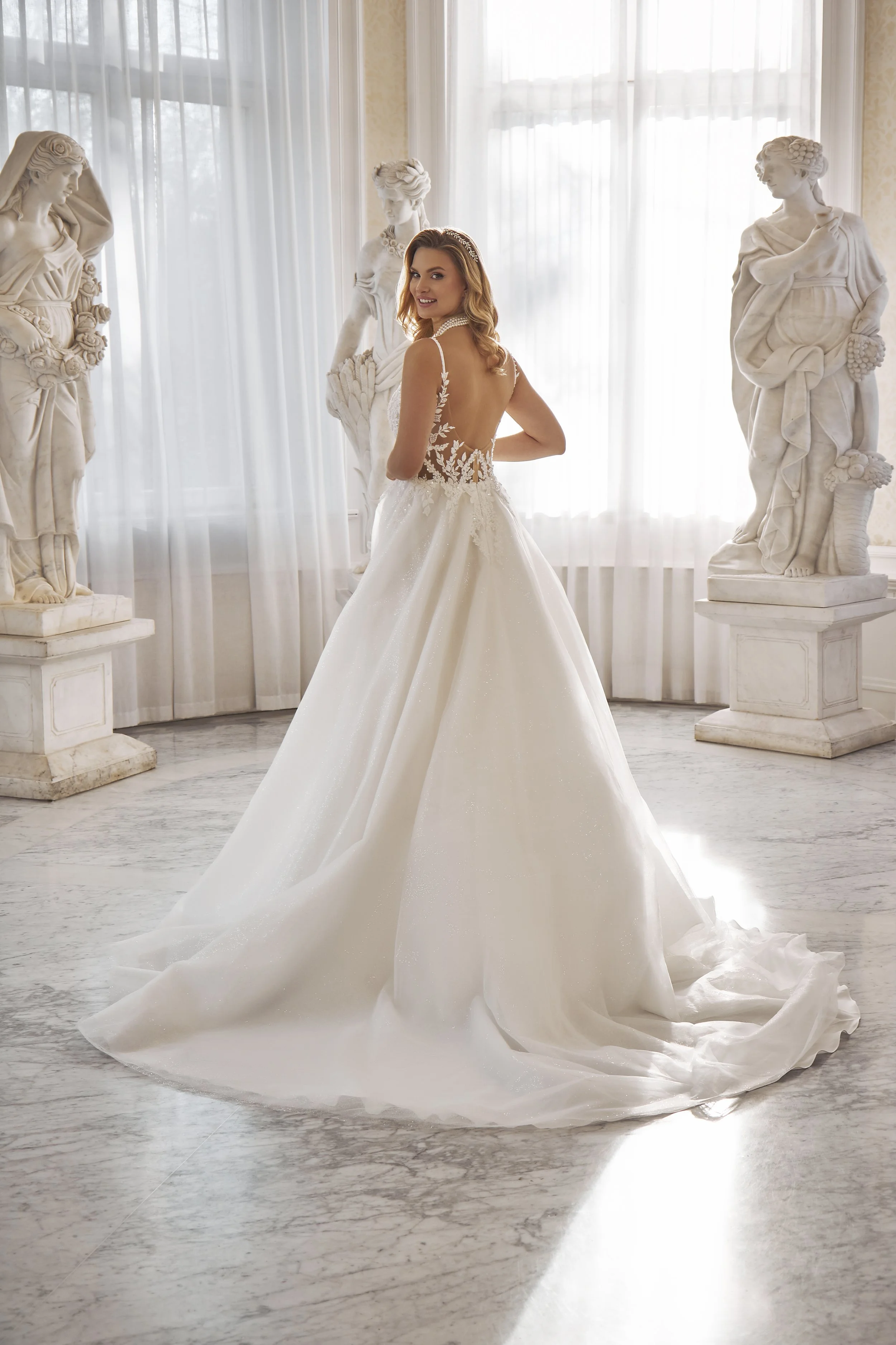 Full back view of Lia Bella Model Tasha showing the low illusion back, voluminous tulle skirt and sweeping train.
