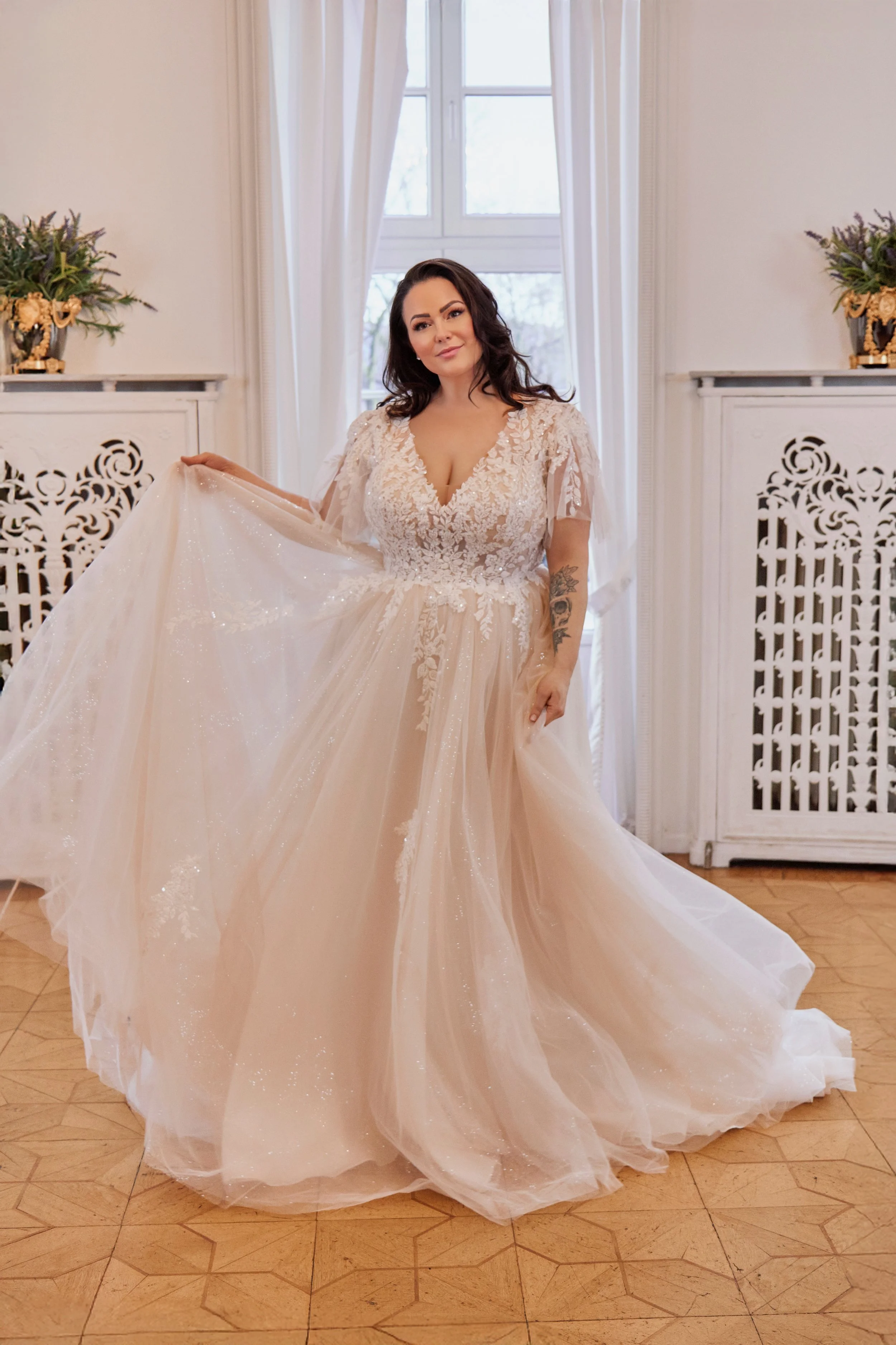 Full front view of Lia Bella Model Tamika, a curvy lace A-line wedding dress with flutter sleeves and a shimmering tulle skirt.