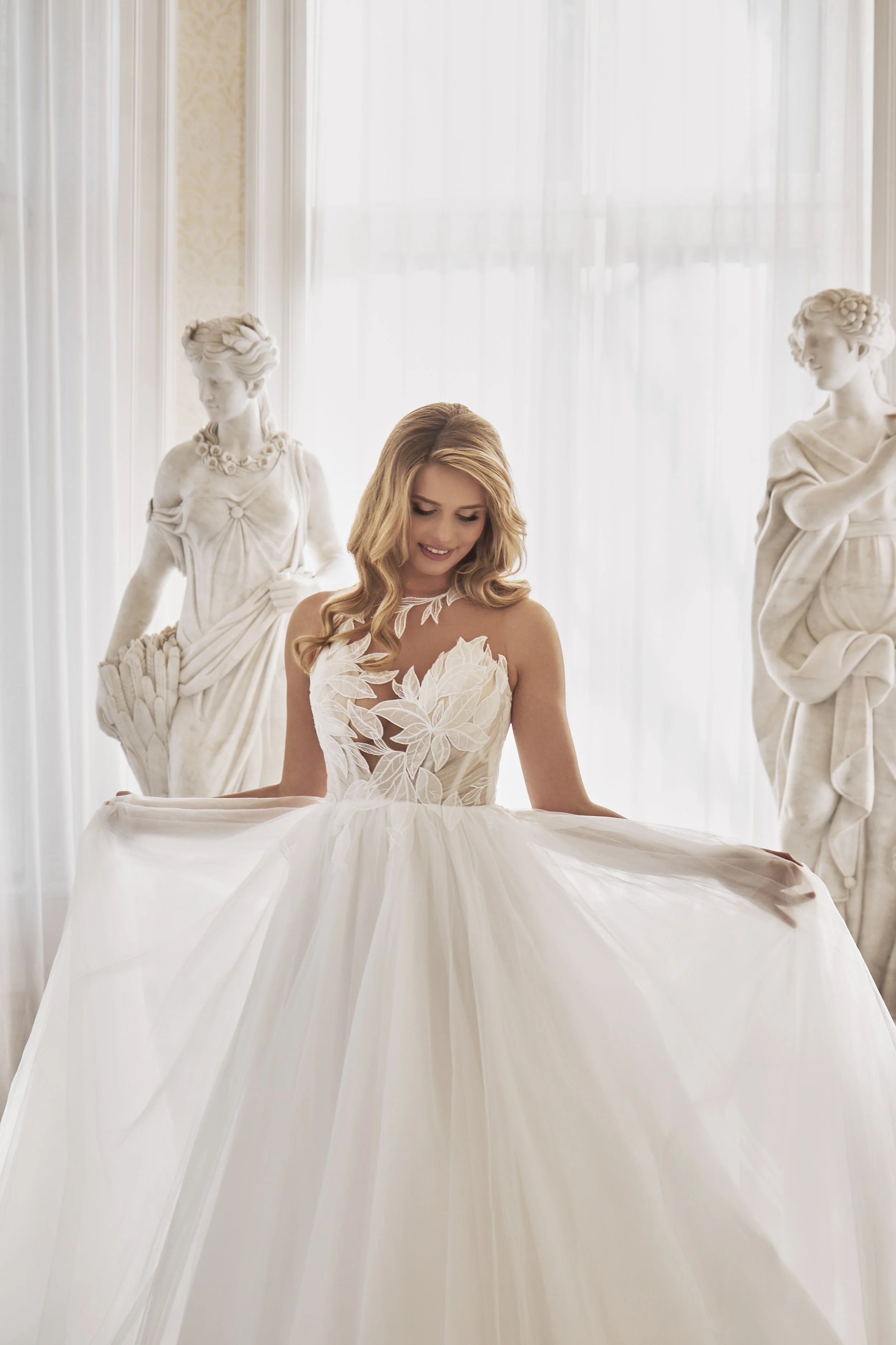 Closer front view of Lia Bella Model Tat featuring a high illusion neckline and oversized botanical lace appliqués.