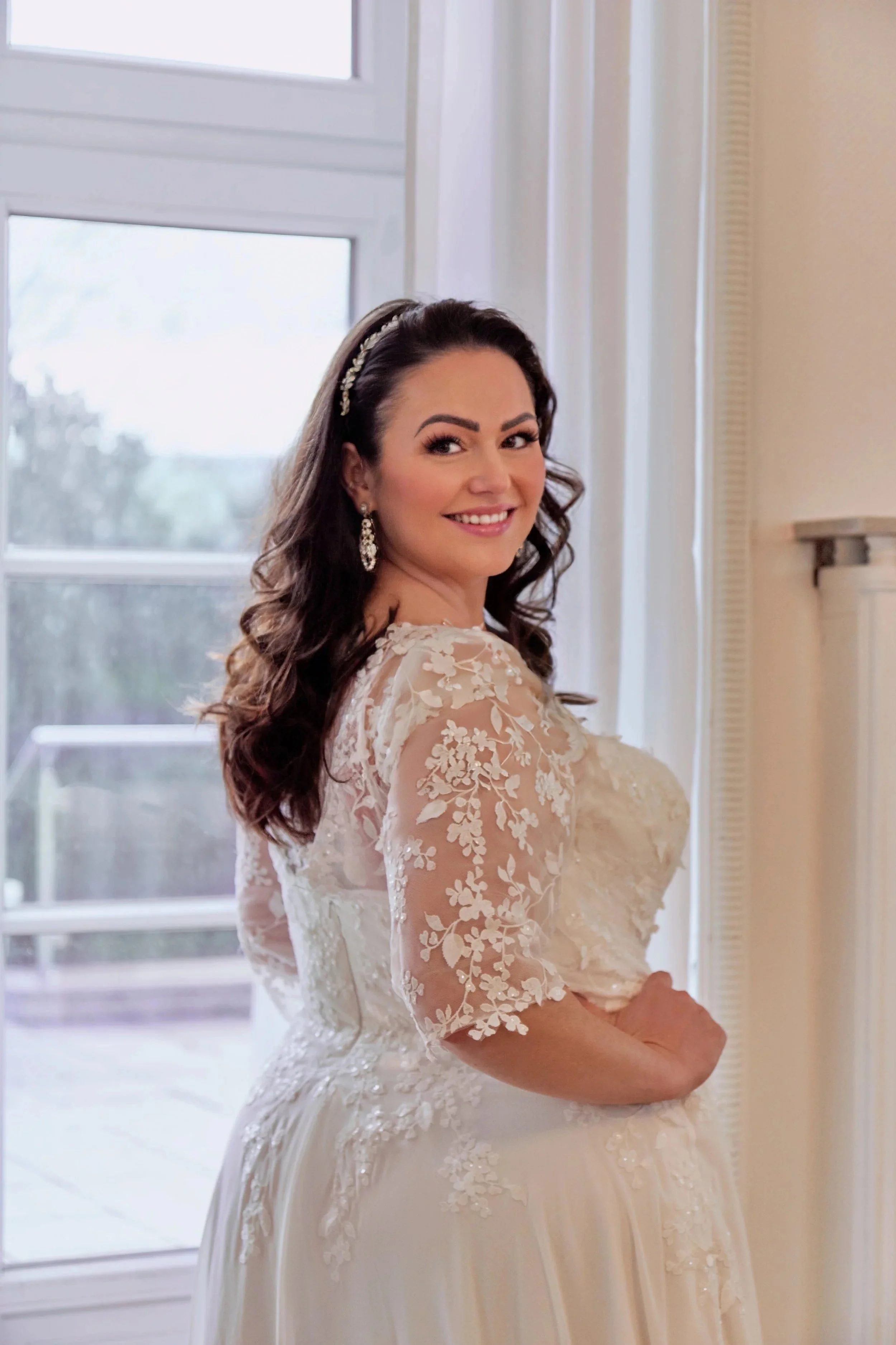 Side detail of Lia Bella Model Trinity featuring a three-quarter illusion sleeve with delicate floral lace and the lace-covered back bodice.